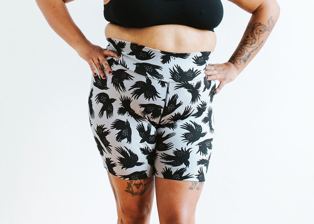 Close up of model wearing Thunderpants Bike Shorts in So it Crows - black crows on grey.
