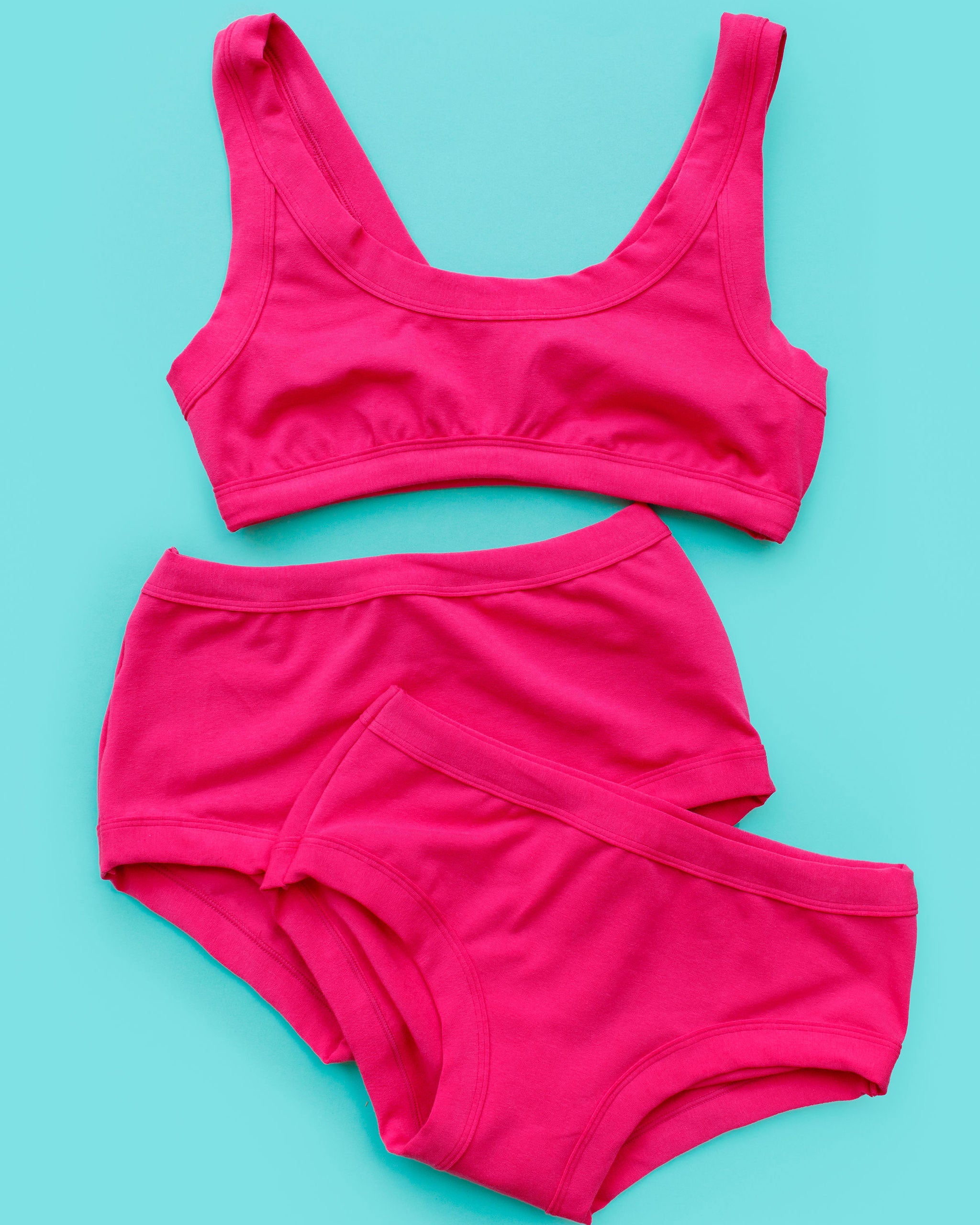Flat lay of Thunderpants Bralette, Original style underwear, and Hipster style underwear in a hot pink color.