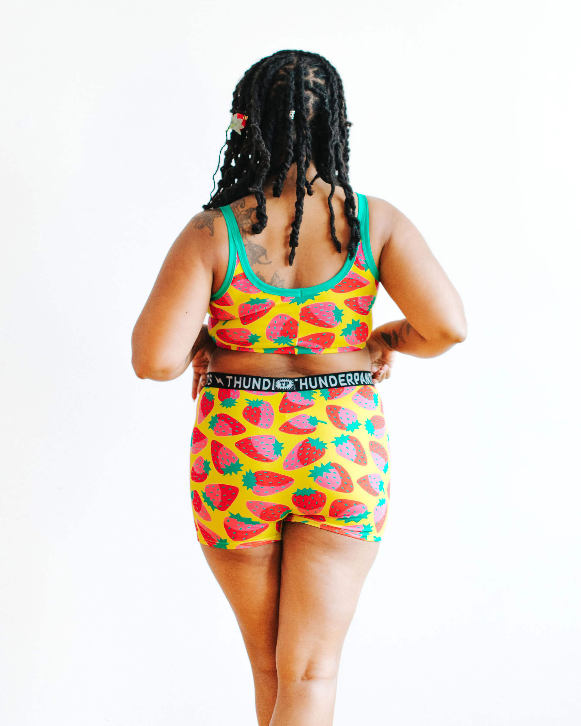 Model wearing Thunderpants Boxer Brief and Longline Bra in a Strawberry print - pink, red, and peacock green on chartreuse.