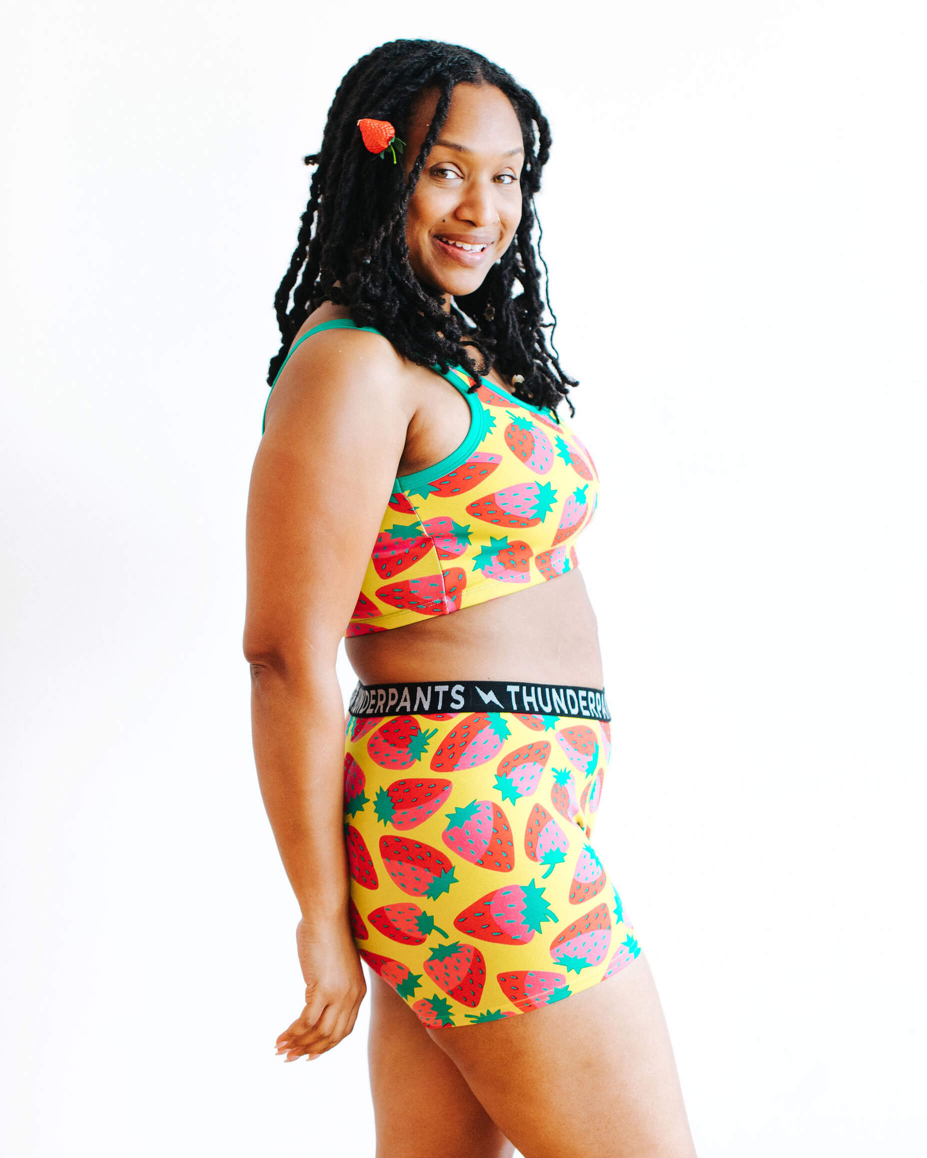 Model wearing Thunderpants Boxer Brief and Longline Bra in a Strawberry print - pink, red, and peacock green on chartreuse.
