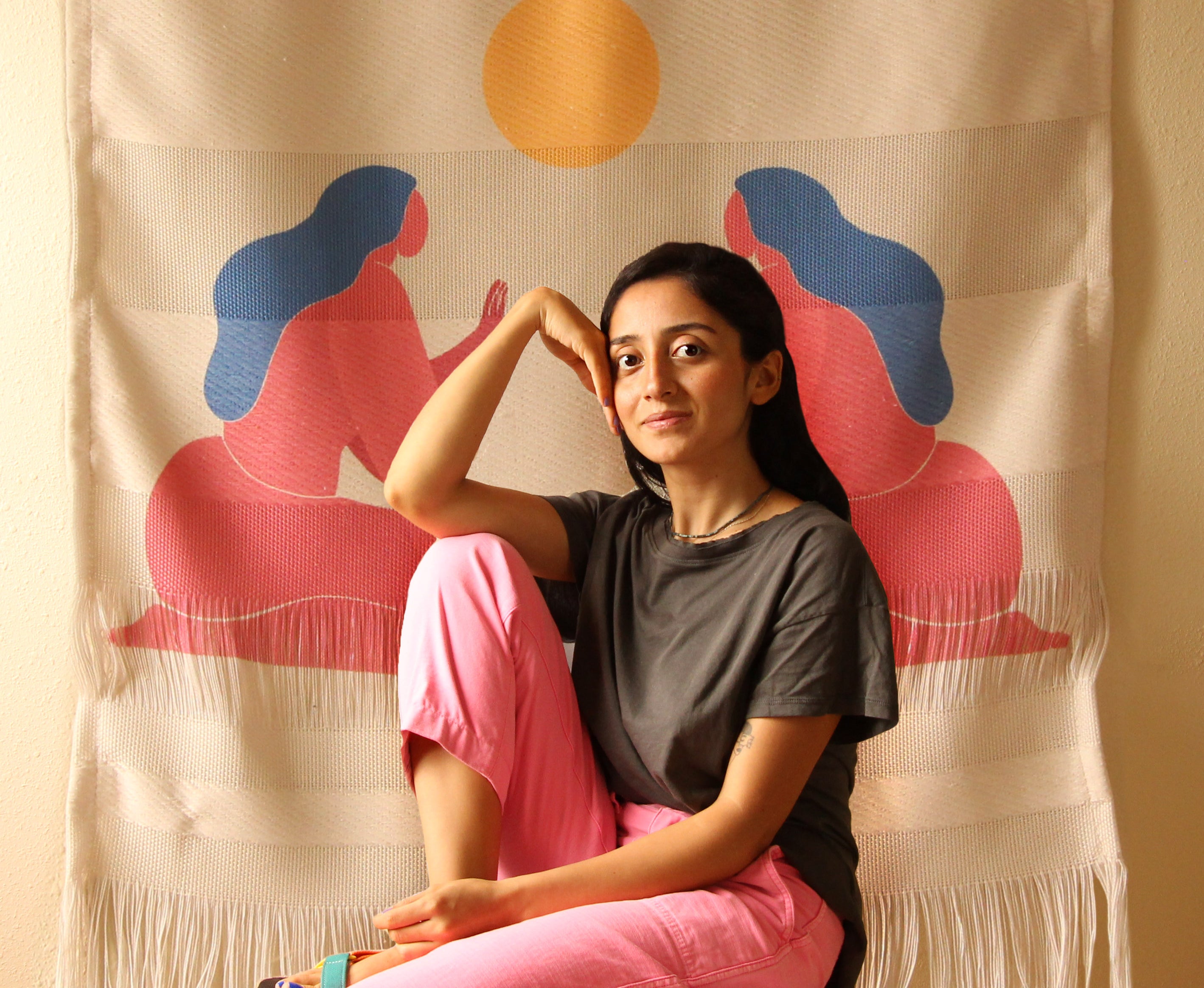 Artist Burcu Köleli sitting in front of her art.