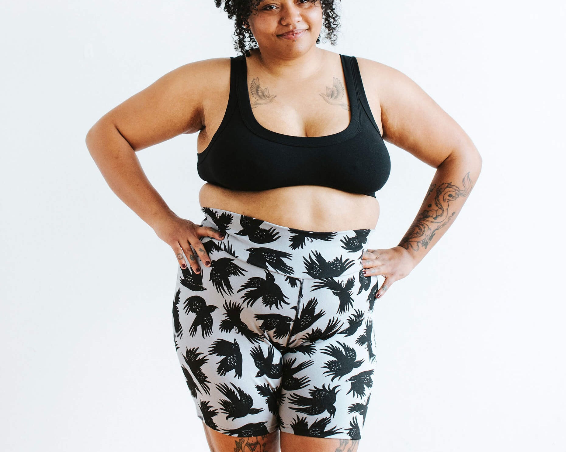Model wearing Thunderpants Bike Shorts in So it Crows - black crows on grey - and Plain Black Bralette.