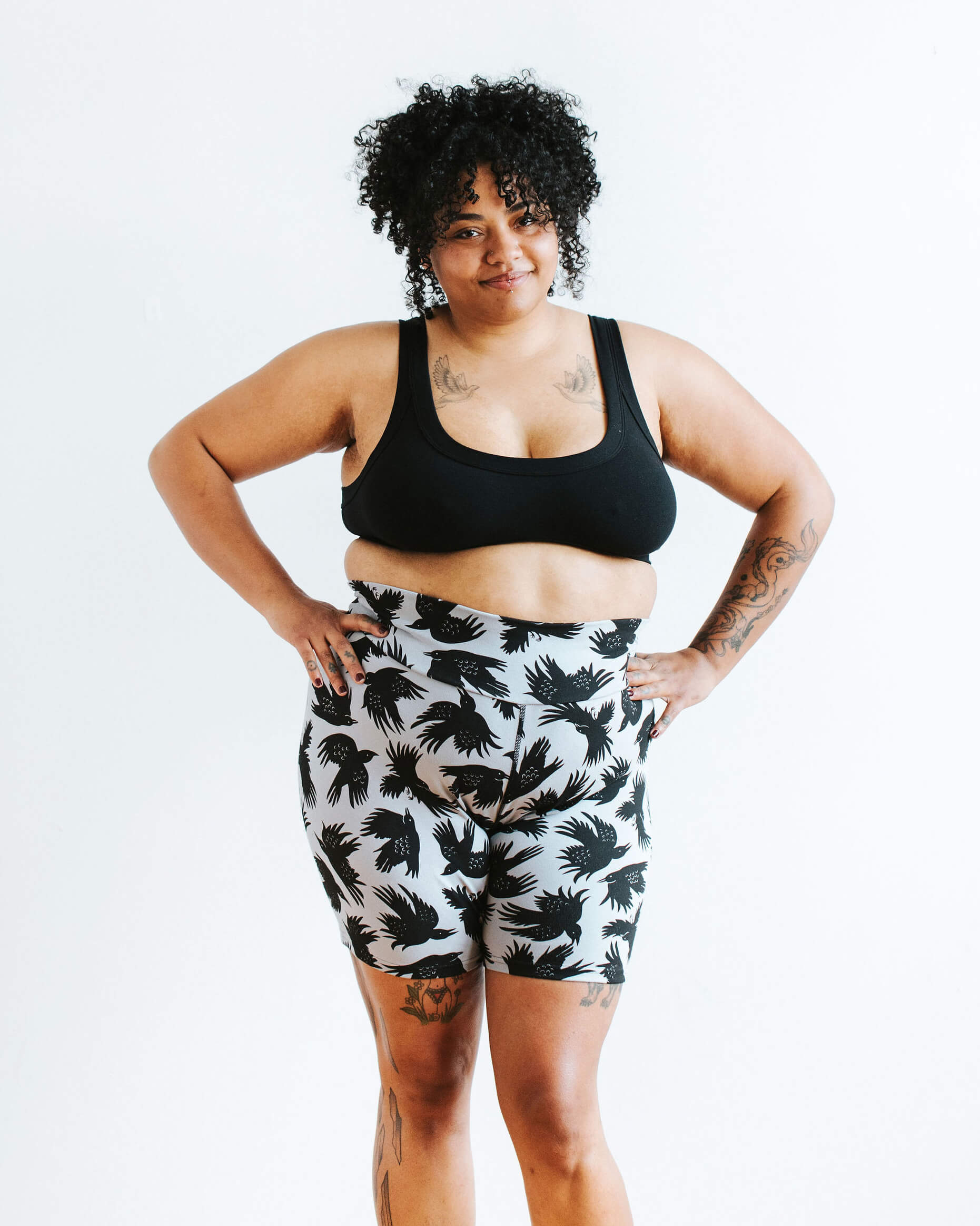 Model wearing Thunderpants Bike Shorts in So it Crows - black crows on grey - and Plain Black Bralette.