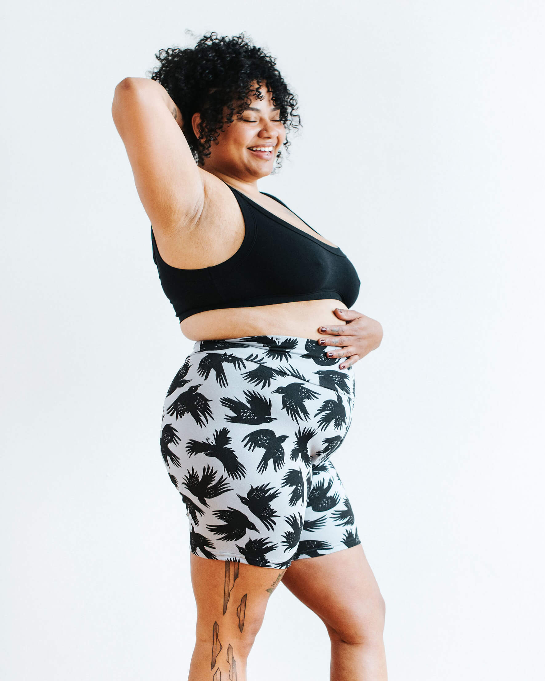 Model wearing Thunderpants Bike Shorts in So it Crows - black crows on grey - and Plain Black Bralette.