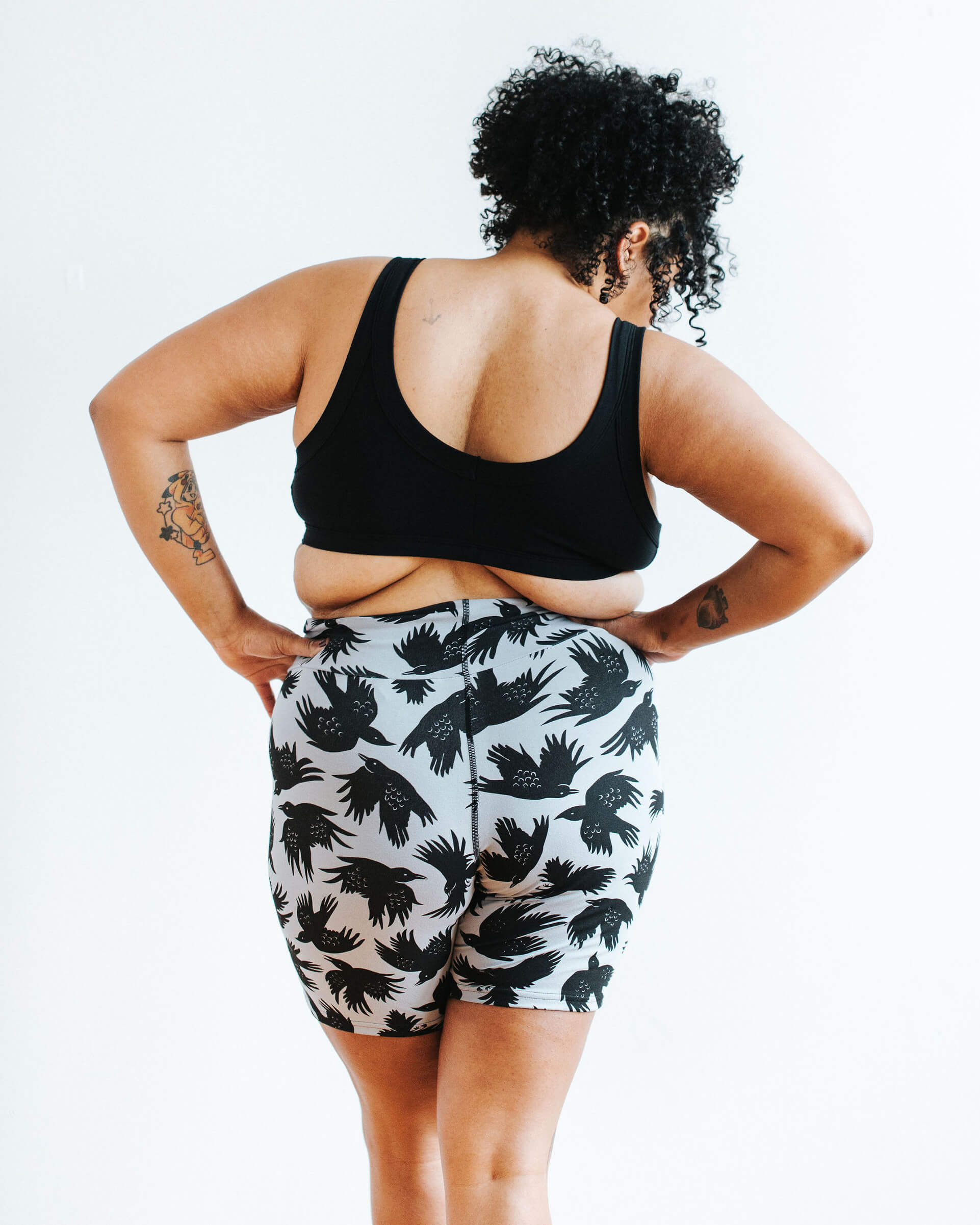 Model wearing Thunderpants Bike Shorts in So it Crows - black crows on grey - and Plain Black Bralette.
