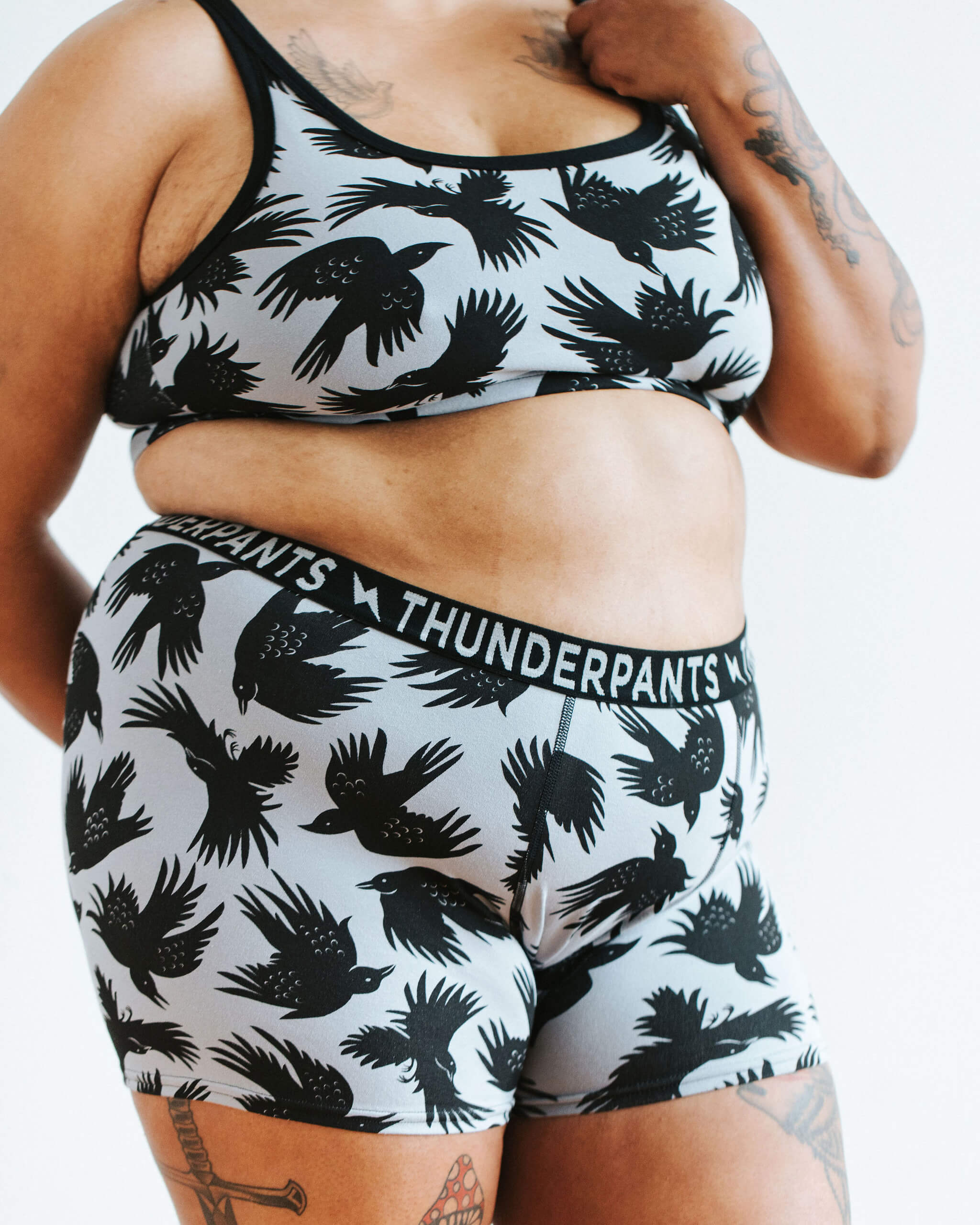 Close up of model wearing Thunderpants Boxer Brief style underwear and Longline Bra in So it Crows print - black crows on grey.