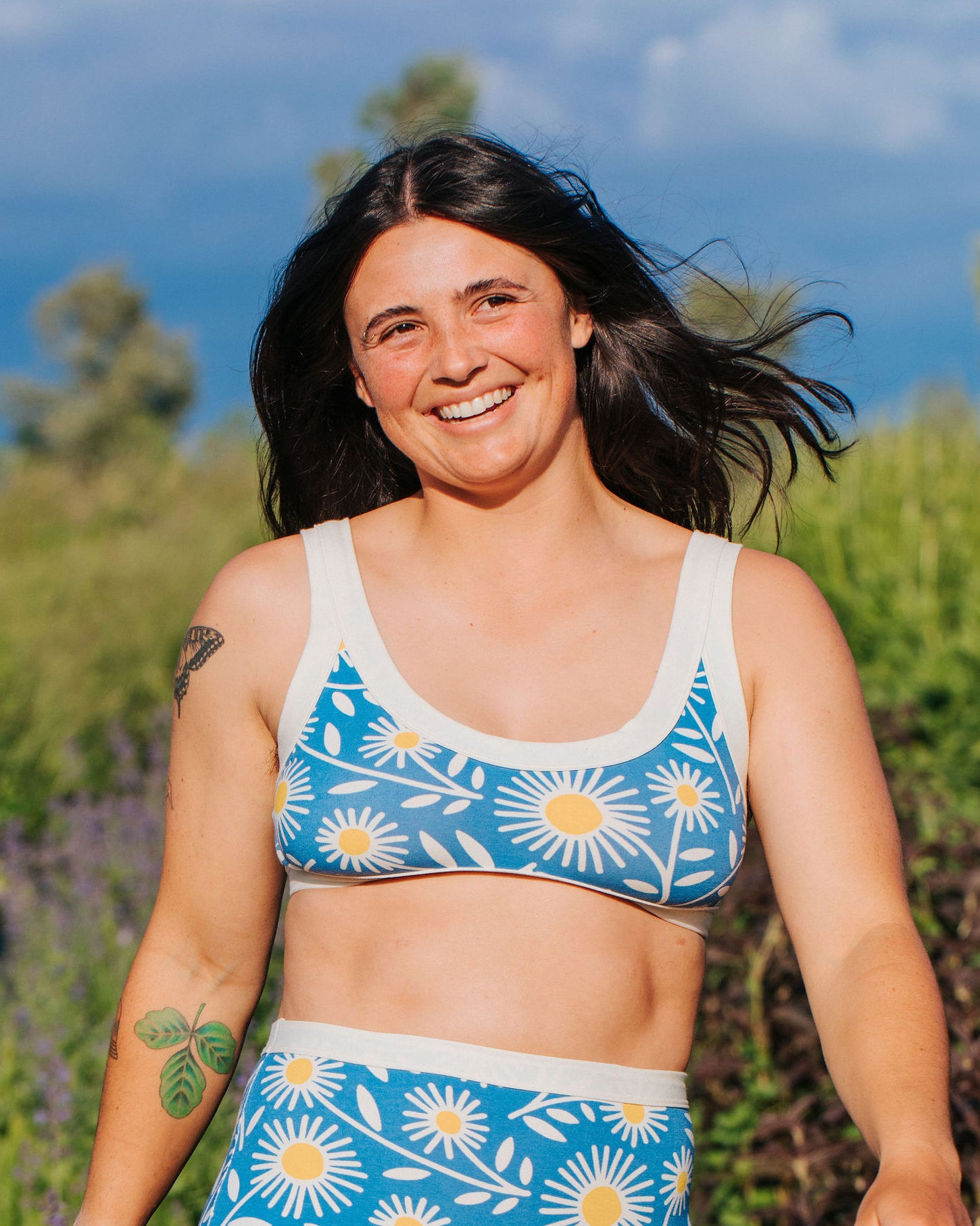 Close up of model wearing Thunderpants Bralette in Daisy Days print: blue with white and yellow daisies.