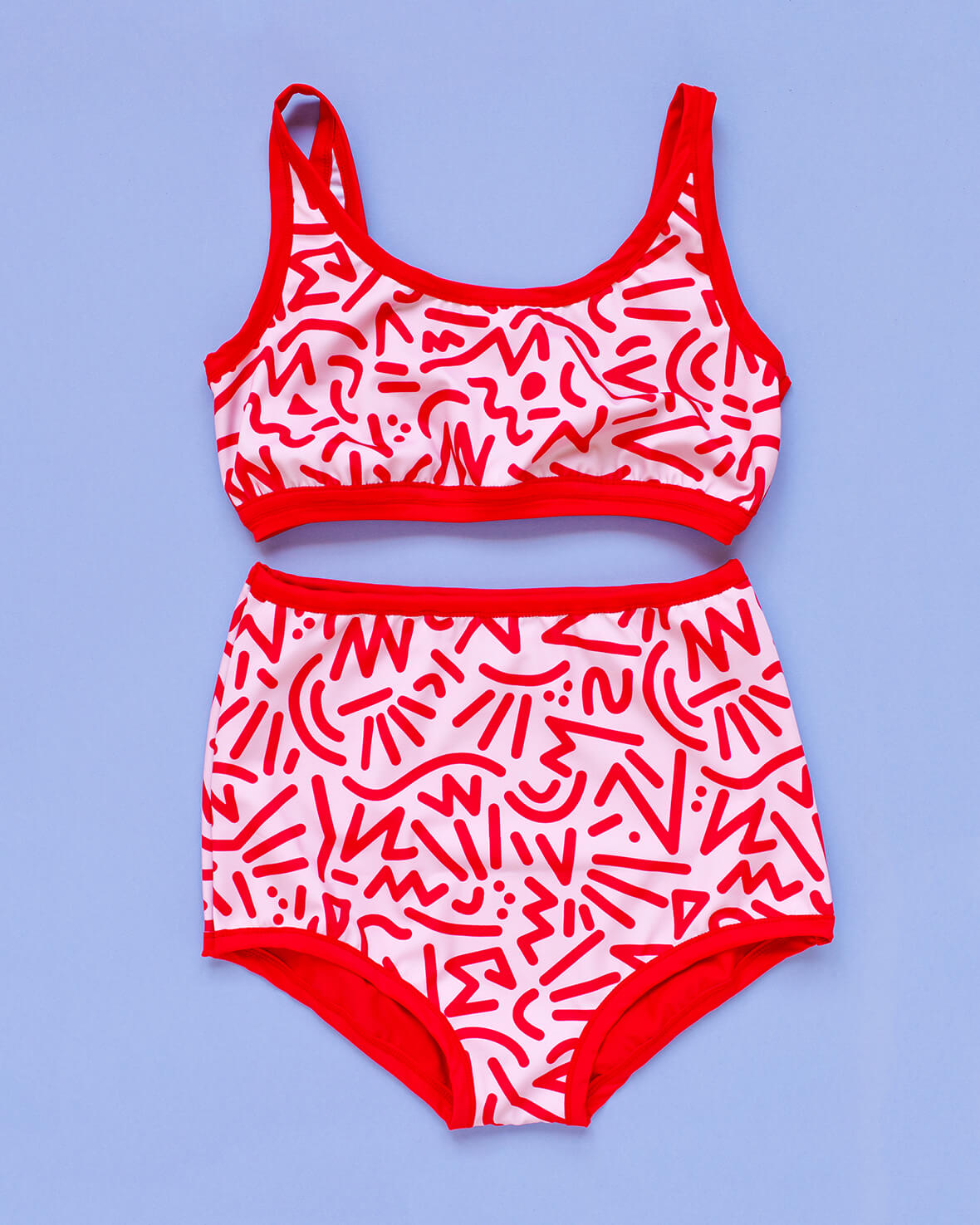 Flat lay of Thunderpants Sky Rise style Swim Bottoms and Swim Top in Energy Vibe print: light pink with dark pink designs.