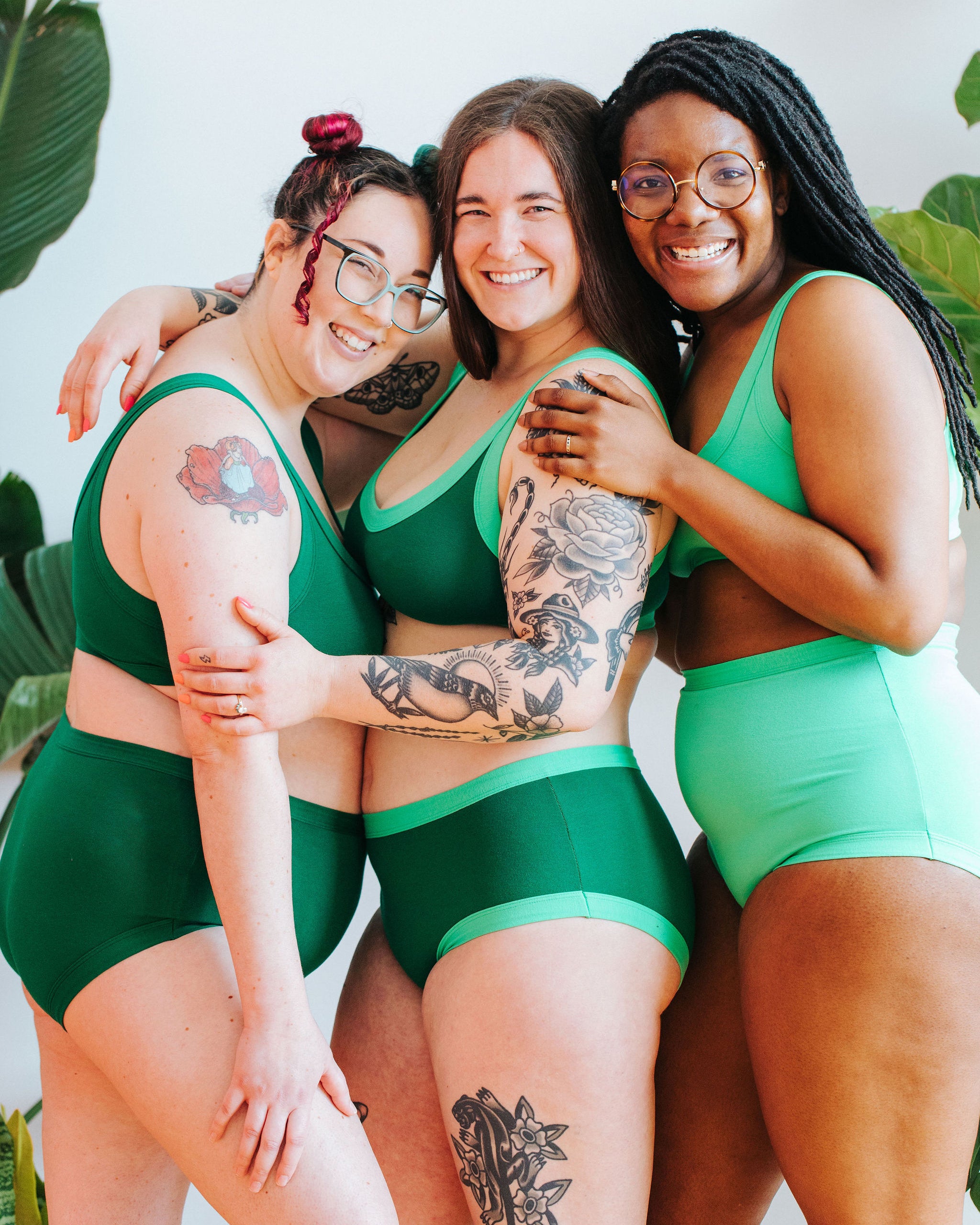 Three models smiling and embracing wearing various items in a mix of Emerald Green, Lime Squeeze, and Sour Apple.