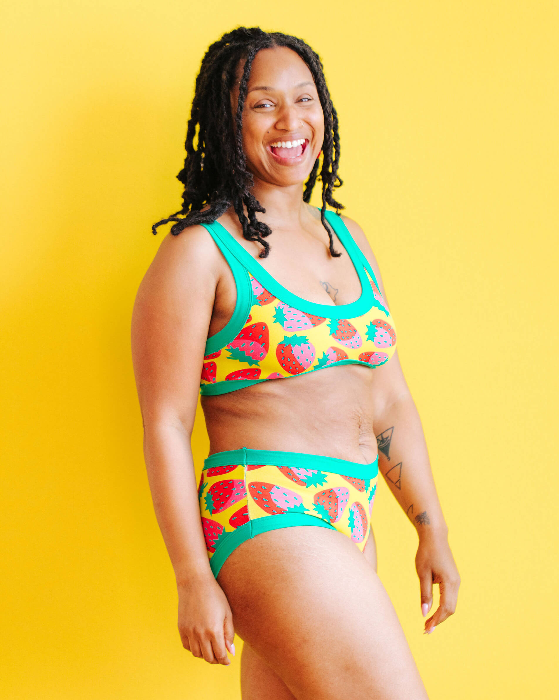 Model wearing Thunderpants Hipster style underwear and Bralette in a Strawberry print - pink, red, and peacock green on chartreuse.