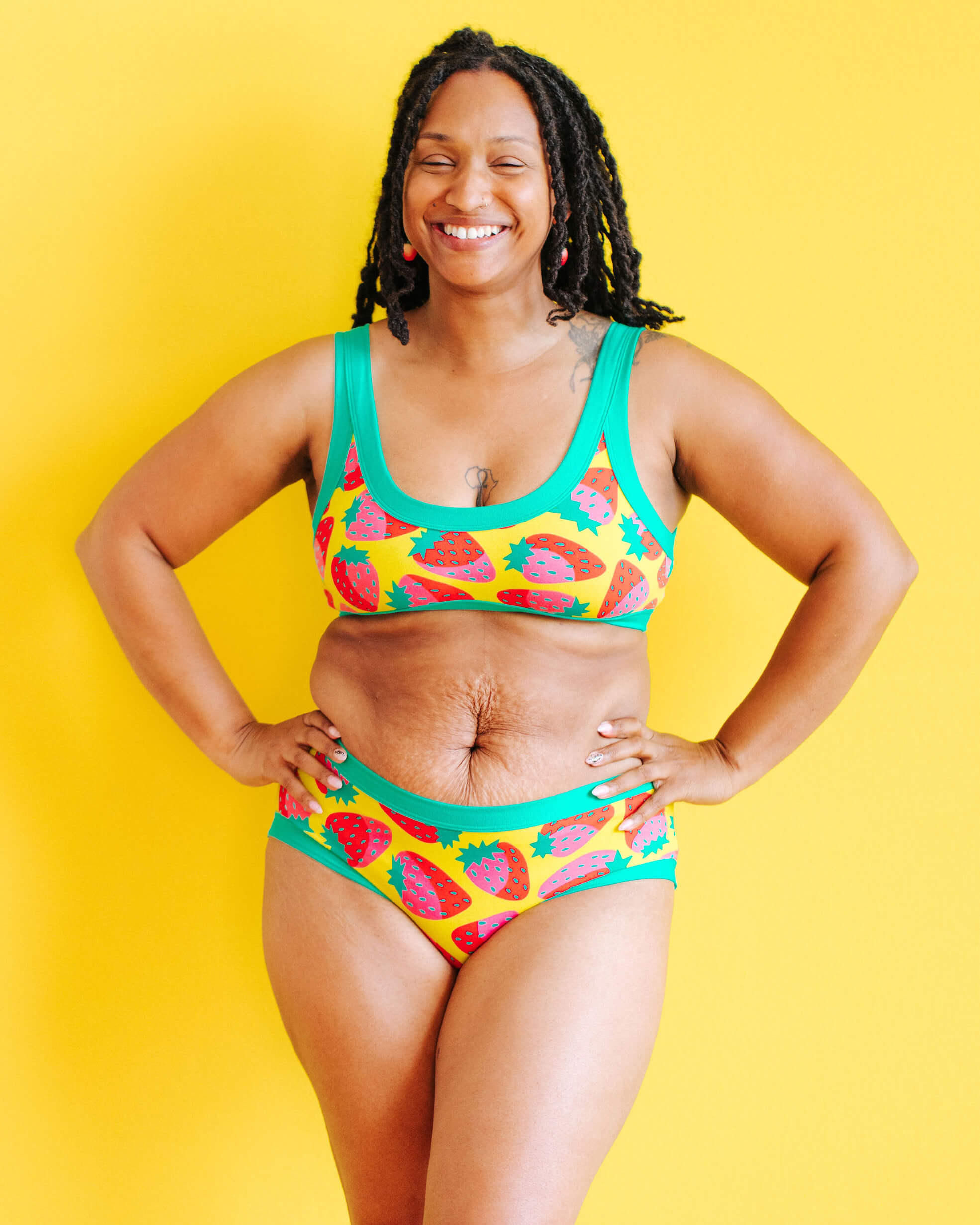 Model wearing Thunderpants Hipster style underwear and Bralette in a Strawberry print - pink, red, and peacock green on chartreuse.
