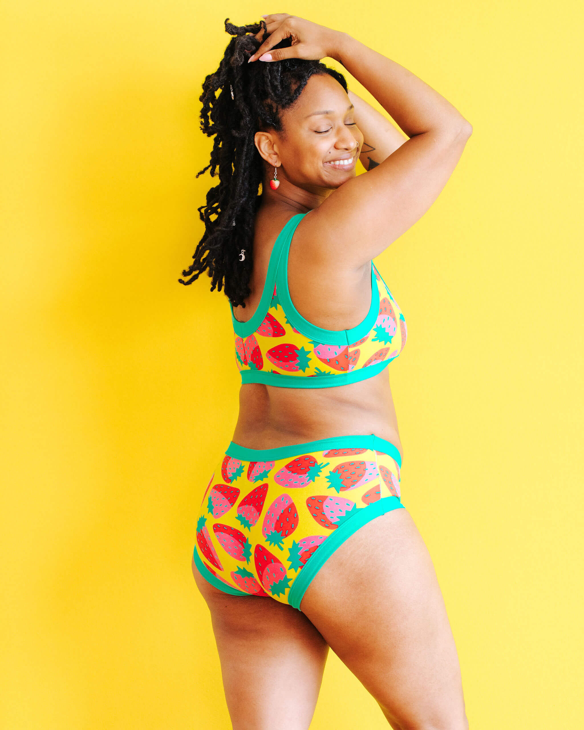 Model wearing Thunderpants Hipster style underwear and Bralette in a Strawberry print - pink, red, and peacock green on chartreuse.
