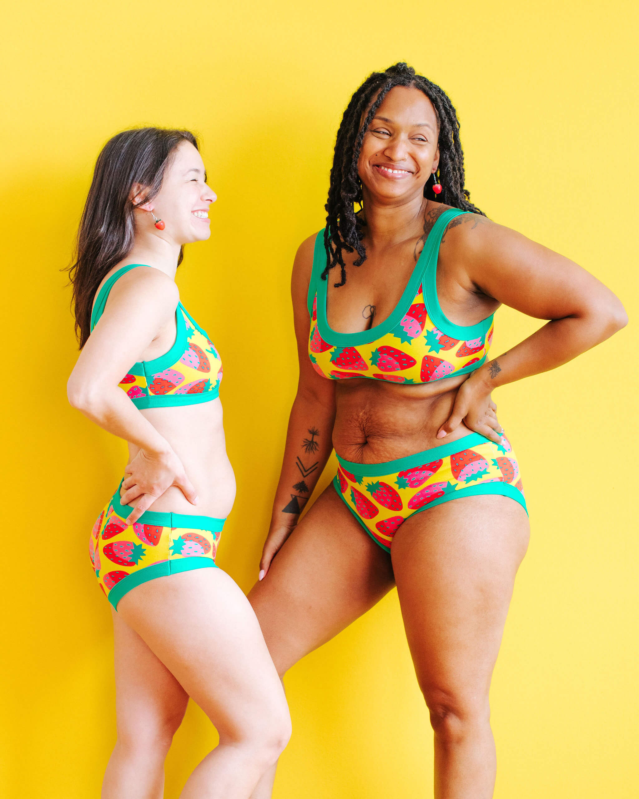 Models wearing Thunderpants Hipster style underwear and Bralette in a Strawberry print - pink, red, and peacock green on chartreuse.