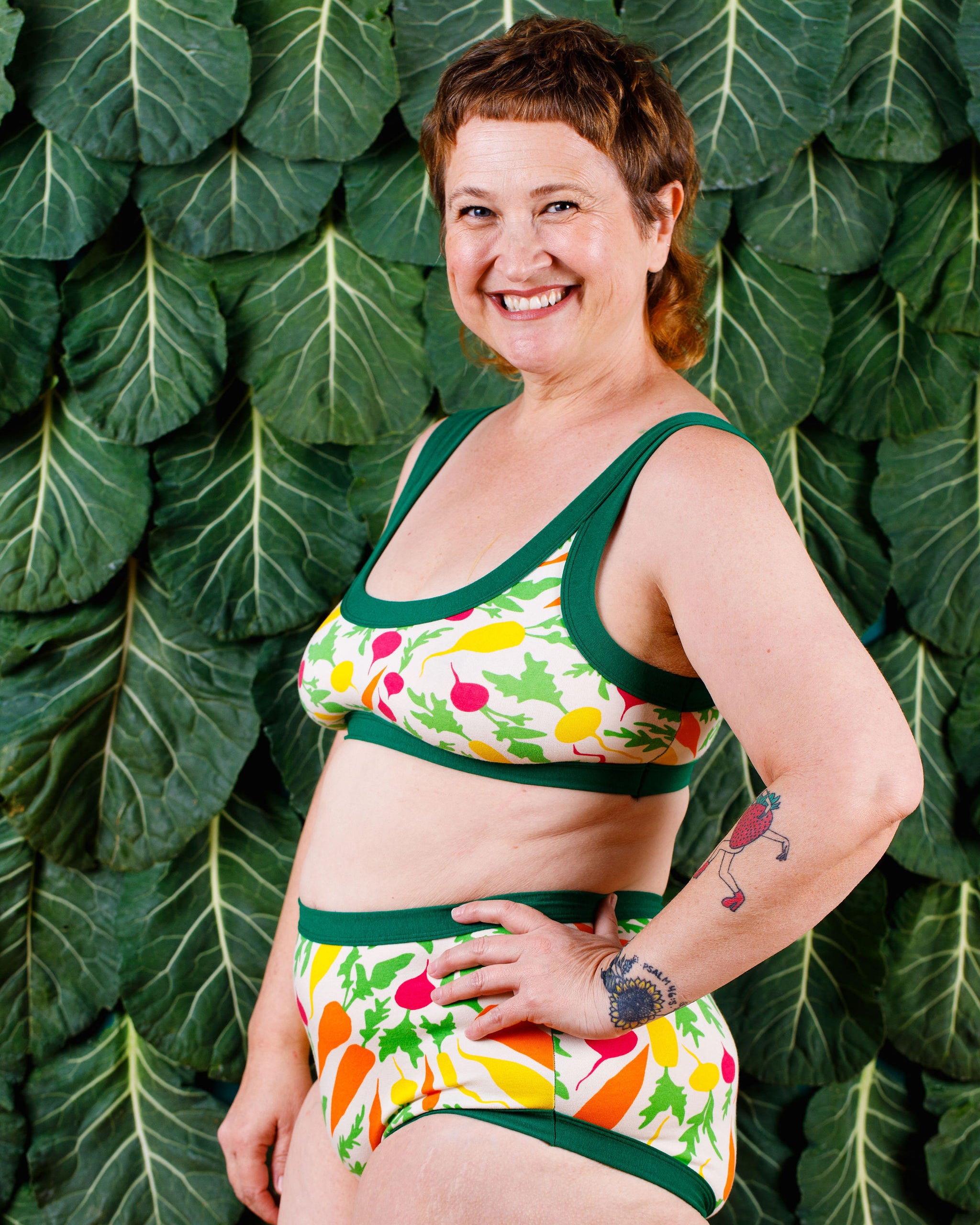 Model smiling wearing Thunderants Bralette and Original style underwear in Root Veggies print - yellow, orange, pink, and green vegetables.
