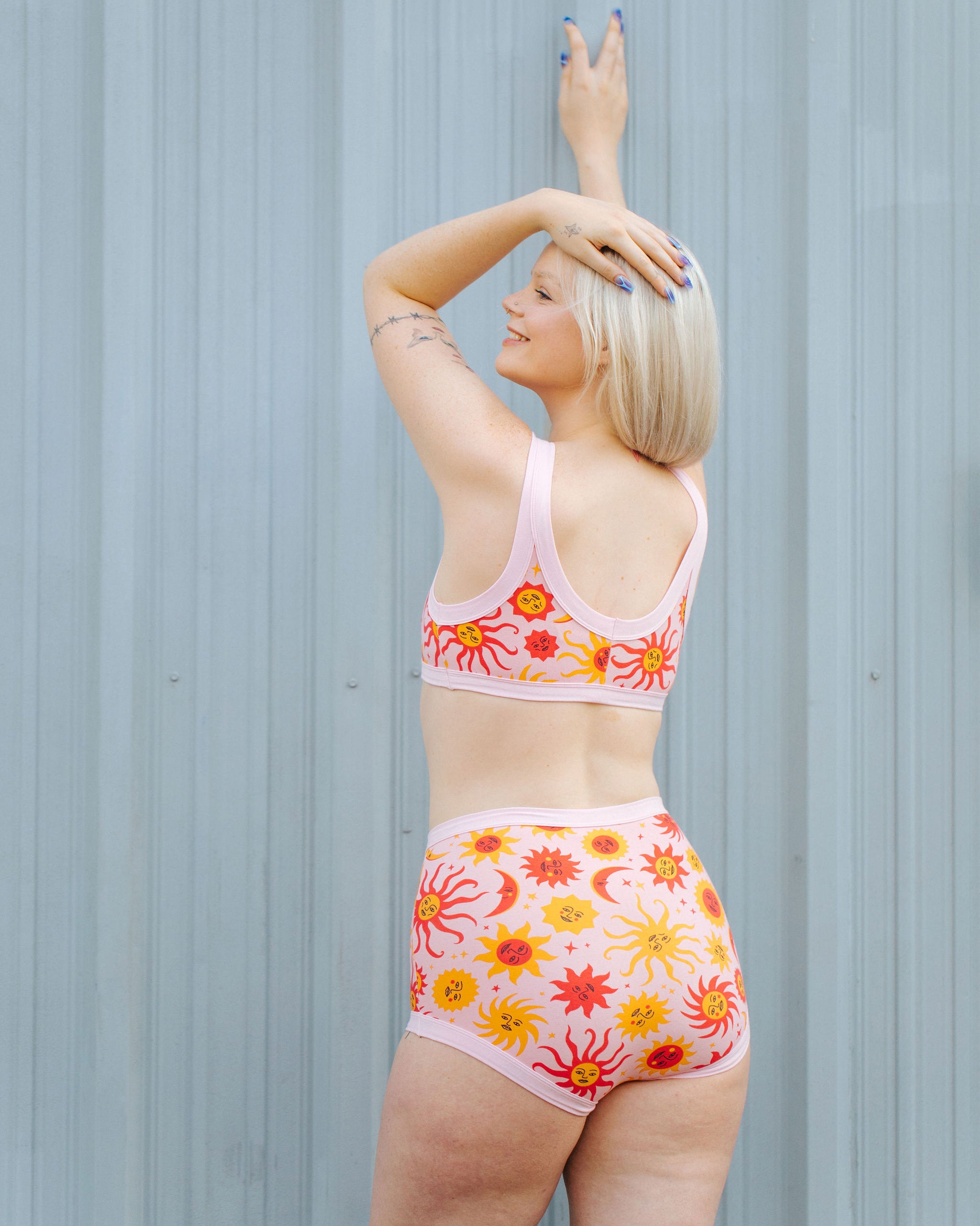 Model wearing Thunderpants Sky Rise style underwear and Bralette in Luna y Sol print - pink, yellow, and orange suns and moons.