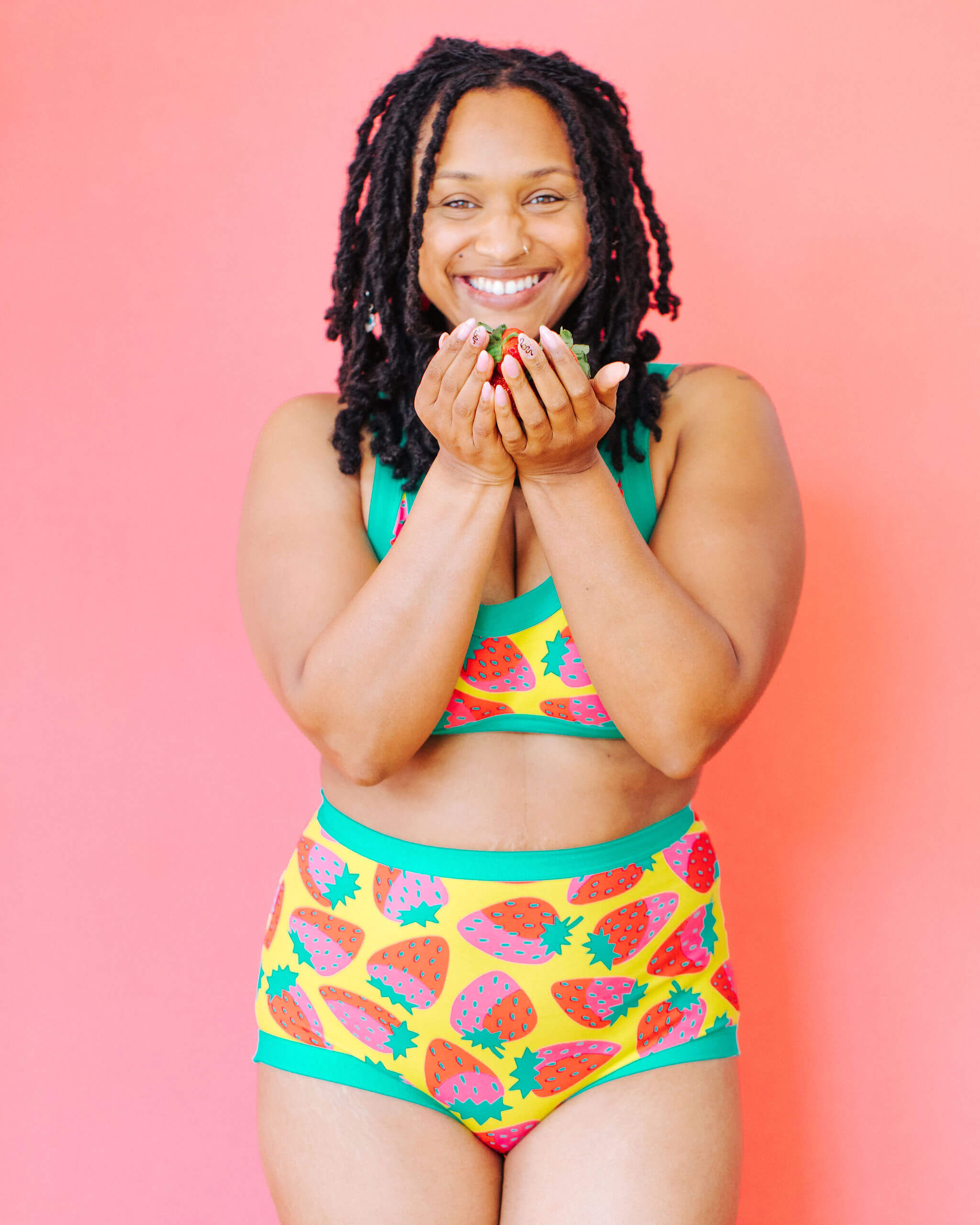 Model wearing Thunderpants Sky Rise style underwear and Bralette in a Strawberry print - pink, red, and peacock green on chartreuse.