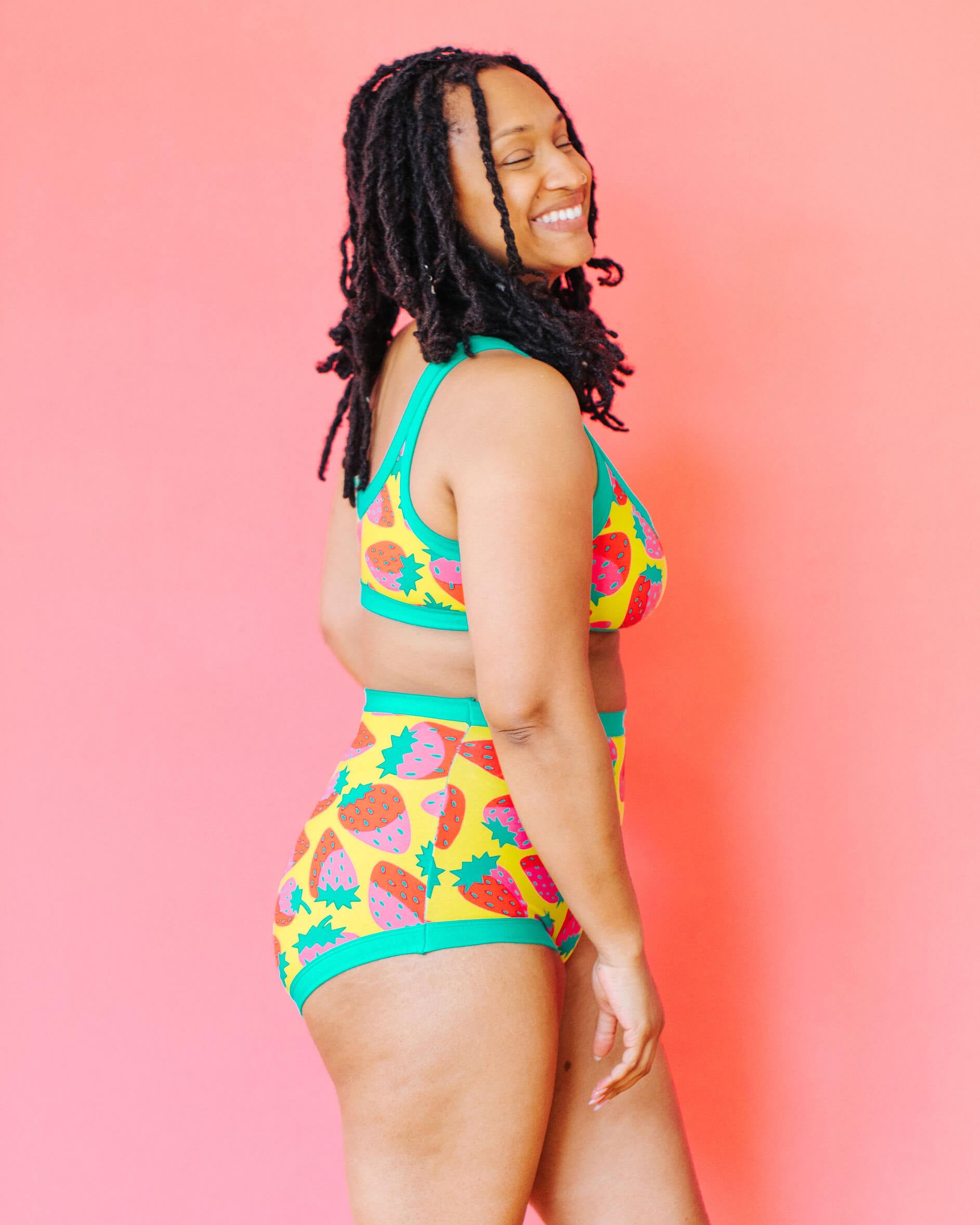 Model wearing Thunderpants Sky Rise style underwear and Bralette in a Strawberry print - pink, red, and peacock green on chartreuse.