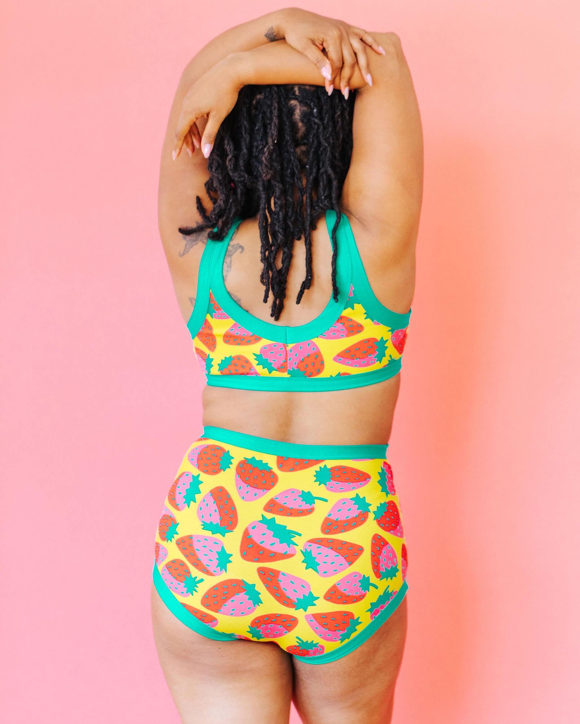 Model wearing Thunderpants Sky Rise style underwear and Bralette in a Strawberry print - pink, red, and peacock green on chartreuse.