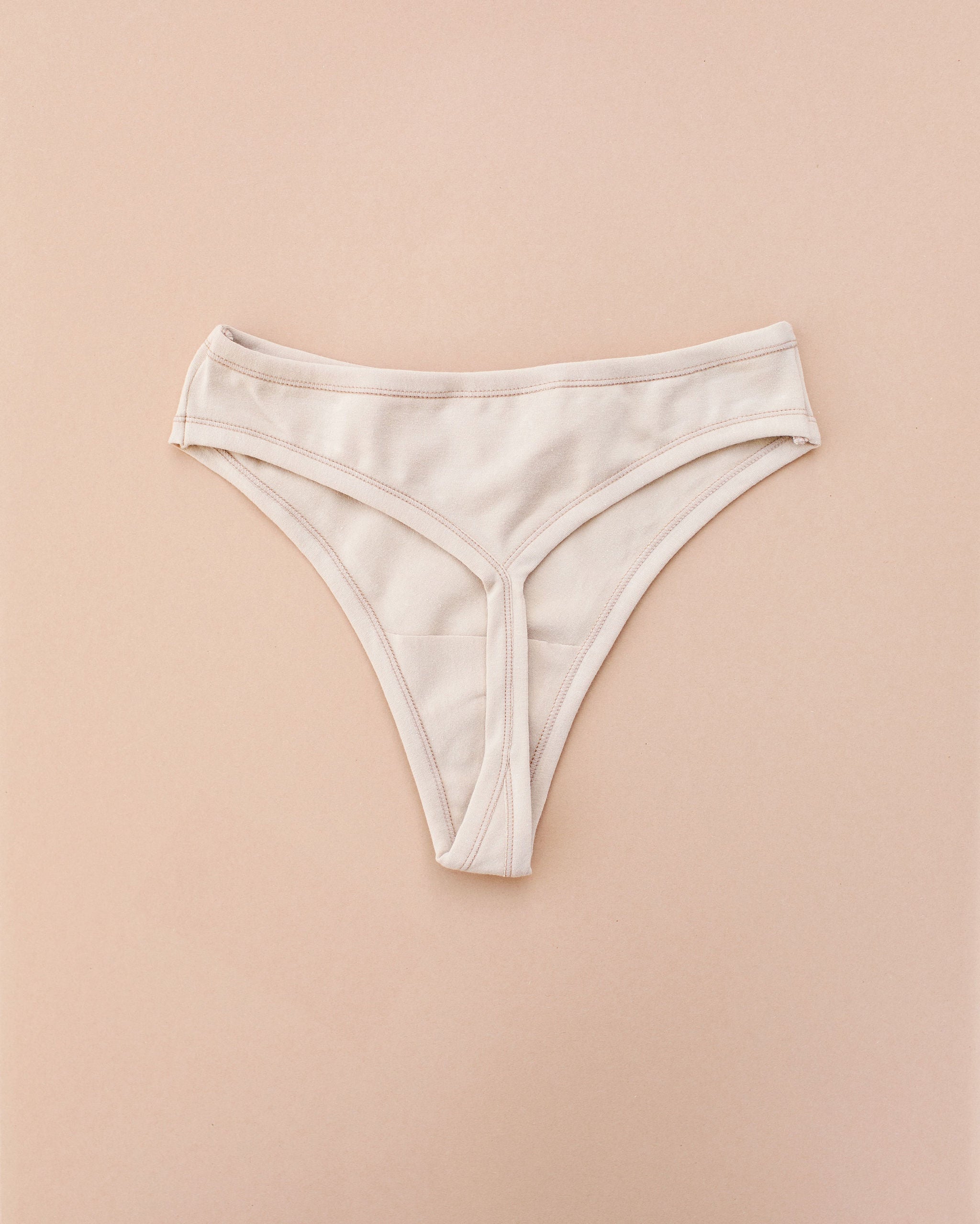 Flay lay of Thunderpants Thong style underwear in Pine Nut - a tan color.