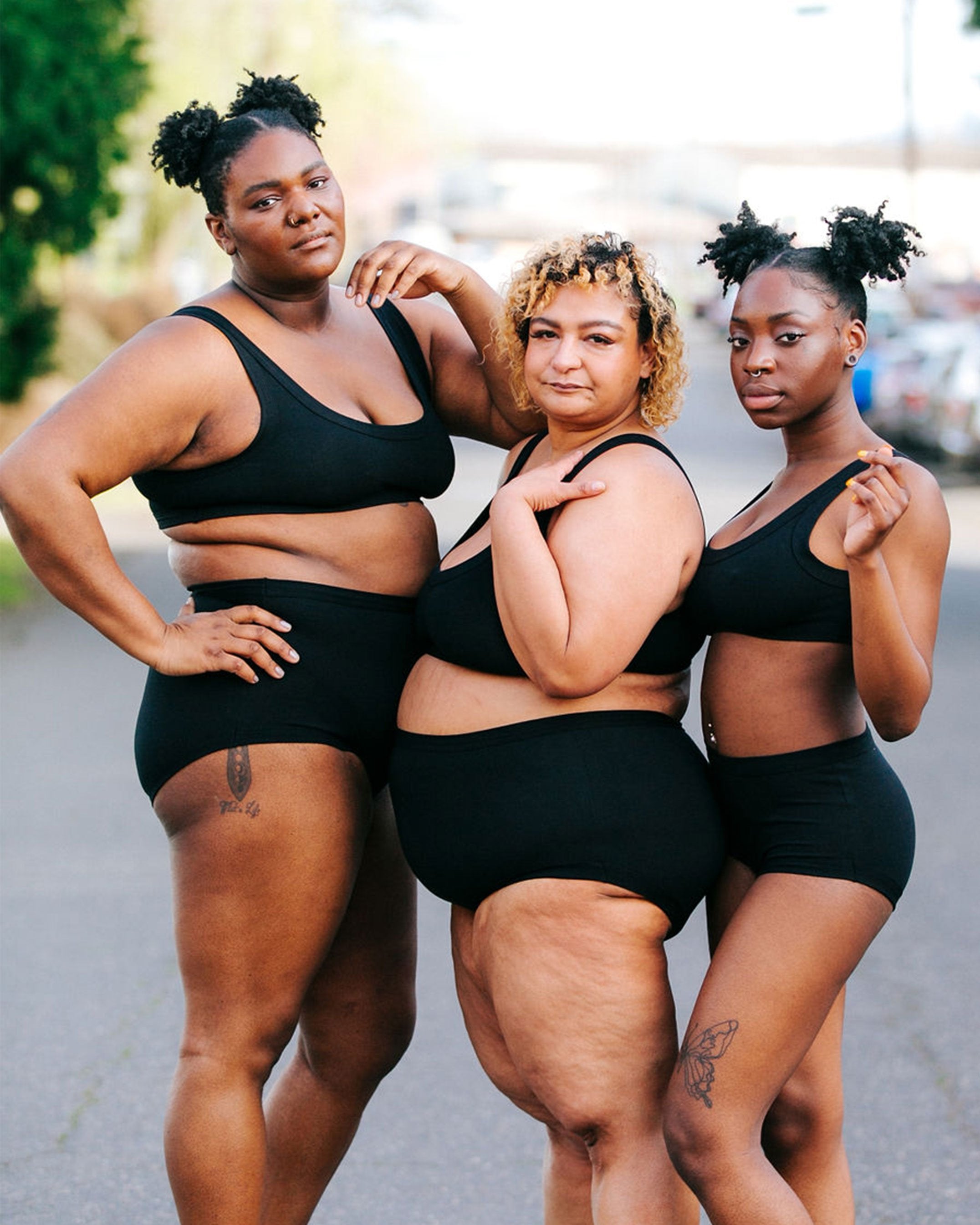 Three beautiful models - two plus sized and one mid-sized wearing Thunderpants organic cotton Original style underwear and Bralettes in plain Black standing outside.