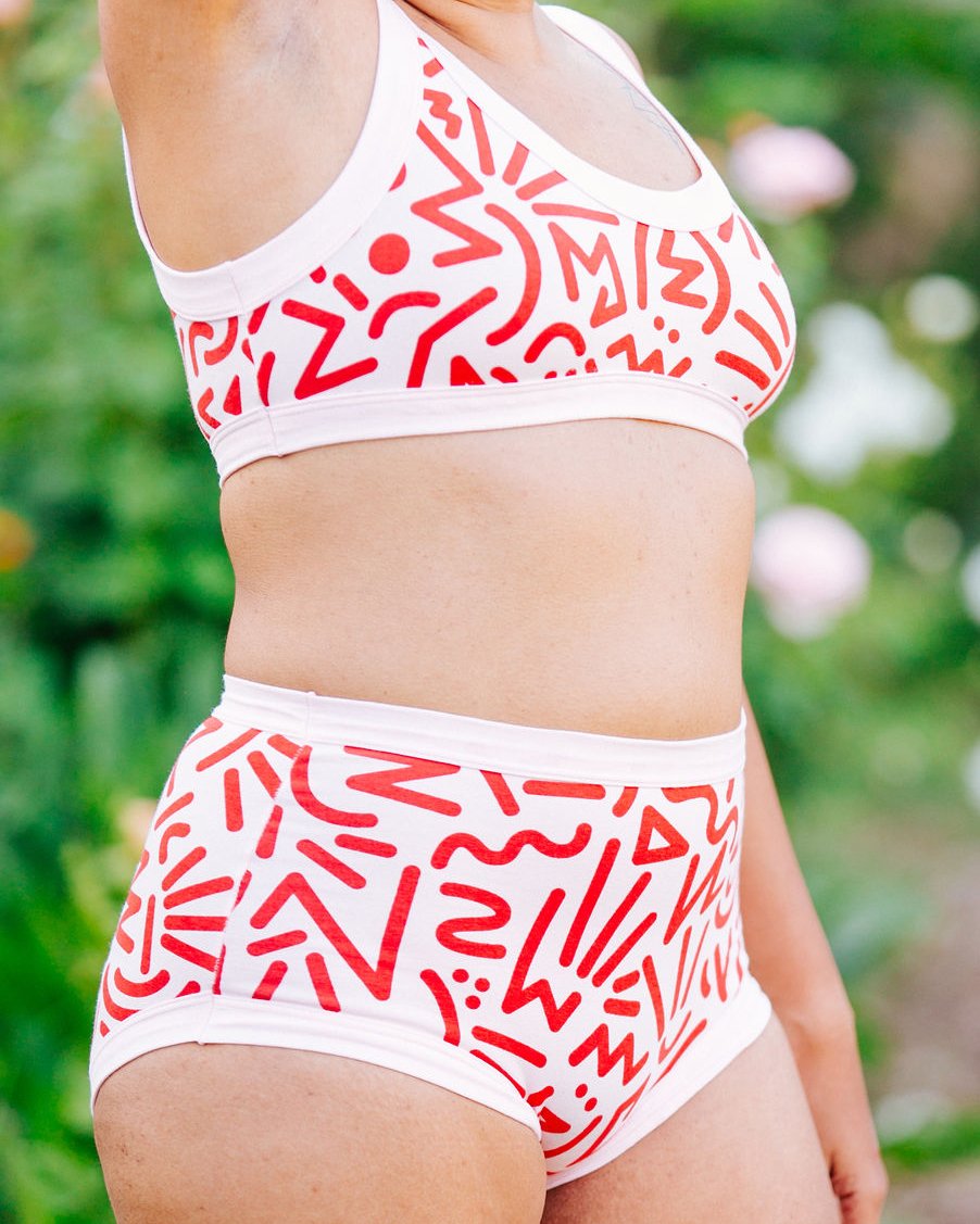 Close up of model wearing Thunderpants Organic Cotton Bralette and Original Style underwear in our Energy Vibes print: Perfect Pink with dark pink large squiggles.