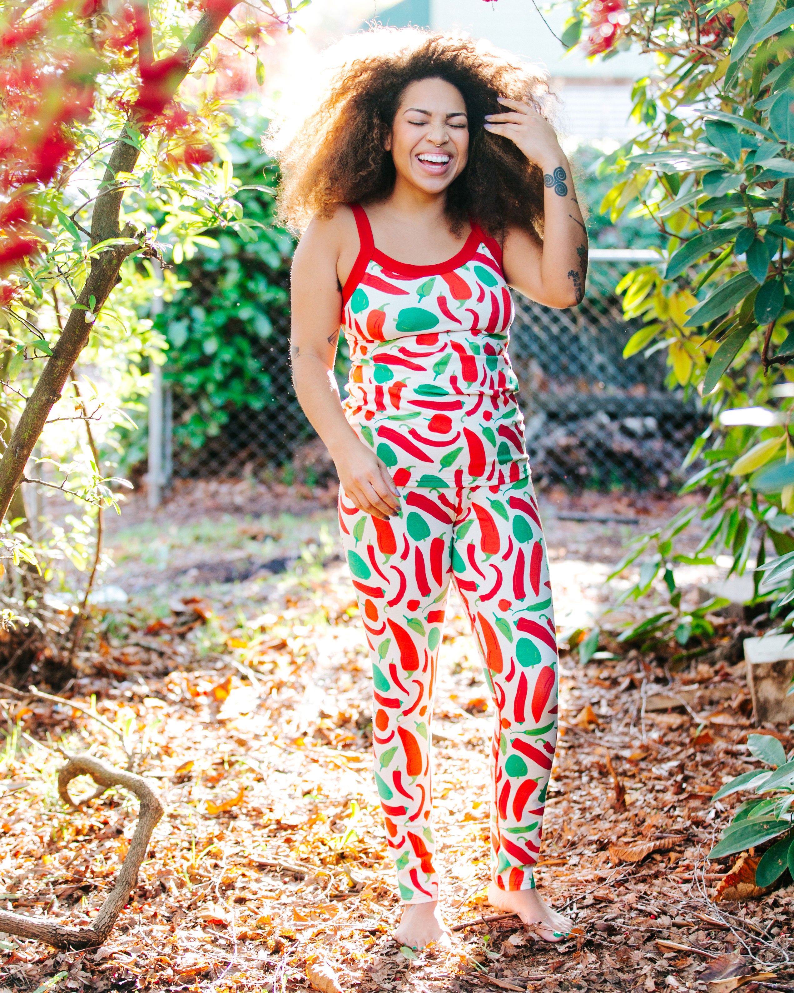 Model laughing outside wearing Thunderpants organic cotton Camisole and Leggings in our Hot Pants print: various green, orange, and red peppers printed on Vanilla with red binding.