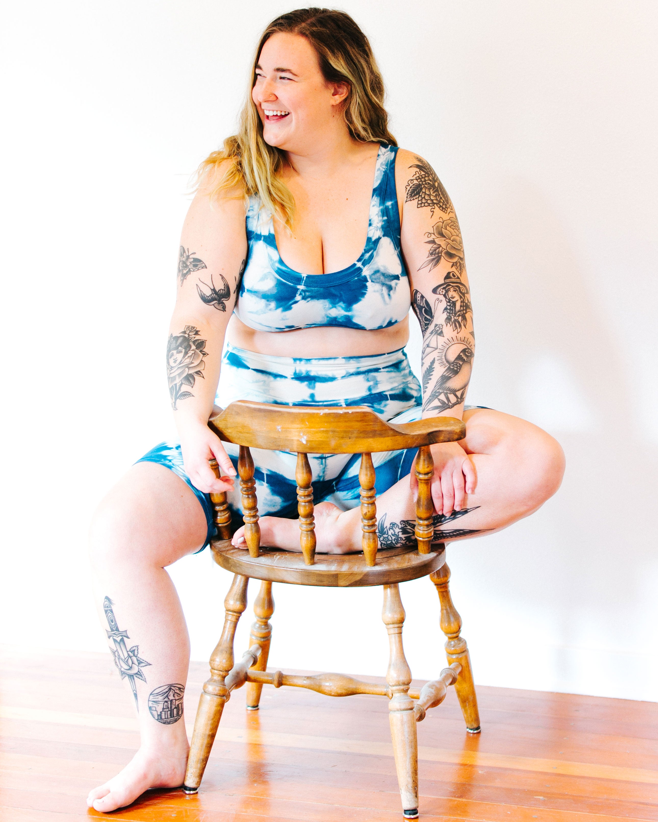 Photo from the front of Thunderpants Organic Cotton Bralette and Bike Shorts in Shibori Hand Dyed Indigo on a model sitting on a wood chair.
