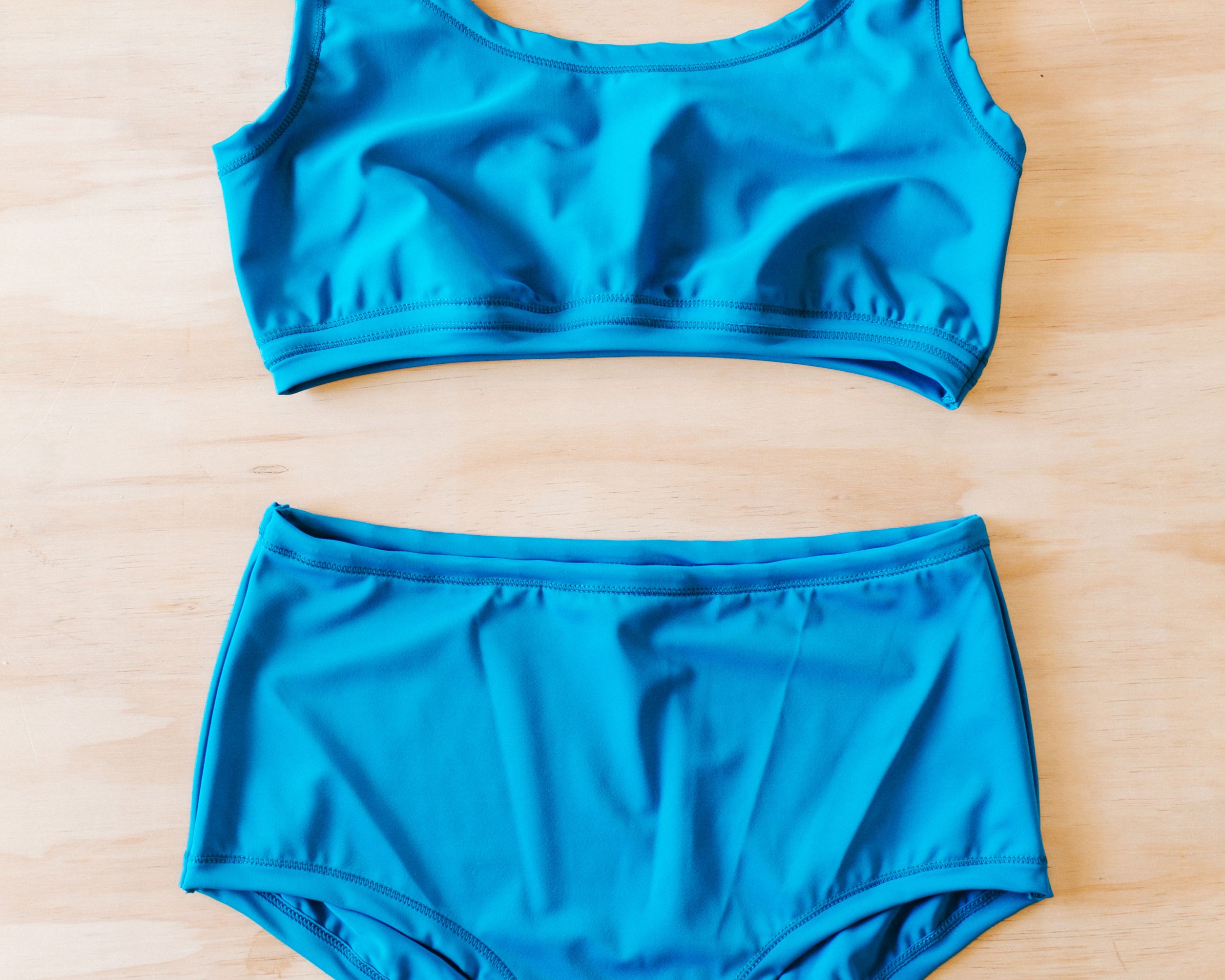 Flat lay on wood surface of Swimwear set with Original style bottoms and top in Marina Blue.
