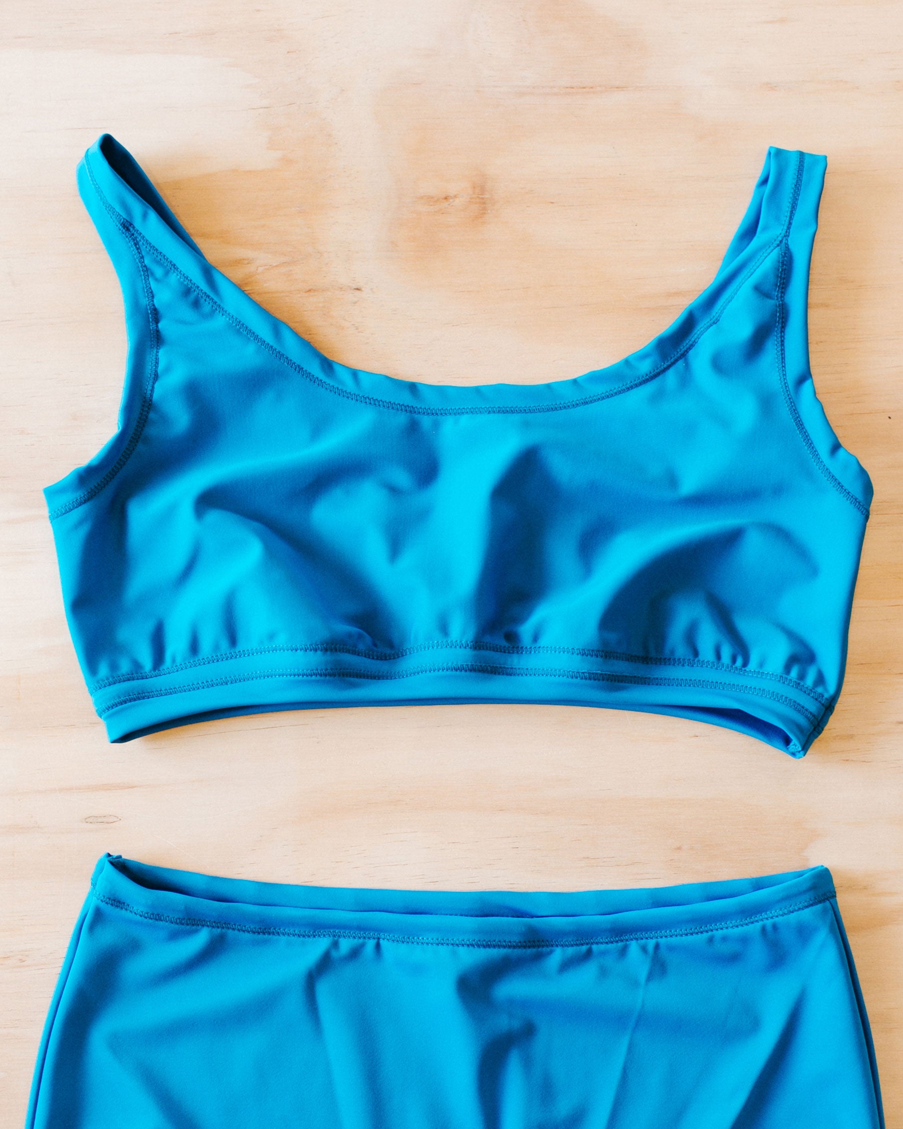 Flat lay on wood surface of Swimwear Top in Marina Blue.