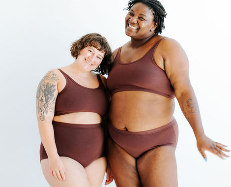 Two models smiling in various Thunderpants items in Chestnut - a dark brown color.