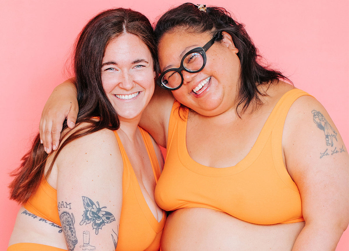 Close up of two models smiling wearing Bralettes in the orange color Oregon Sunstone.