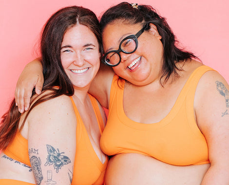 Close up of two models smiling wearing Bralettes in the orange color Oregon Sunstone.