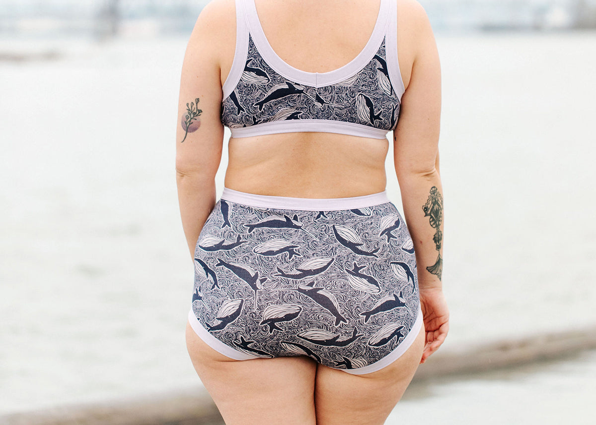 Model wearing Thunderpants Sky Rise style underwear and Bralette in Whale, Whale, Whale - whales in indigo on lavender.