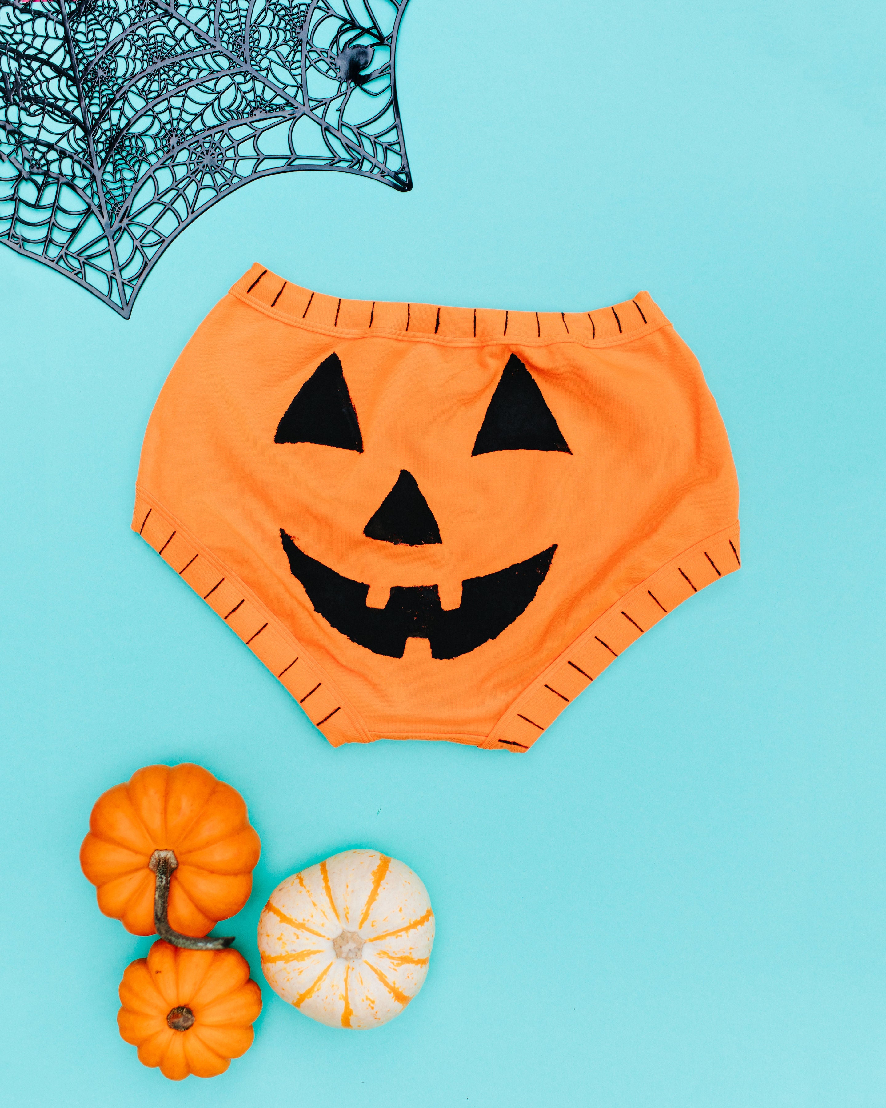 Flat lay of the back of Thunderpants Original style underwear in Oregon Sunstone with a hand printed black Jack-O-Lantern face.