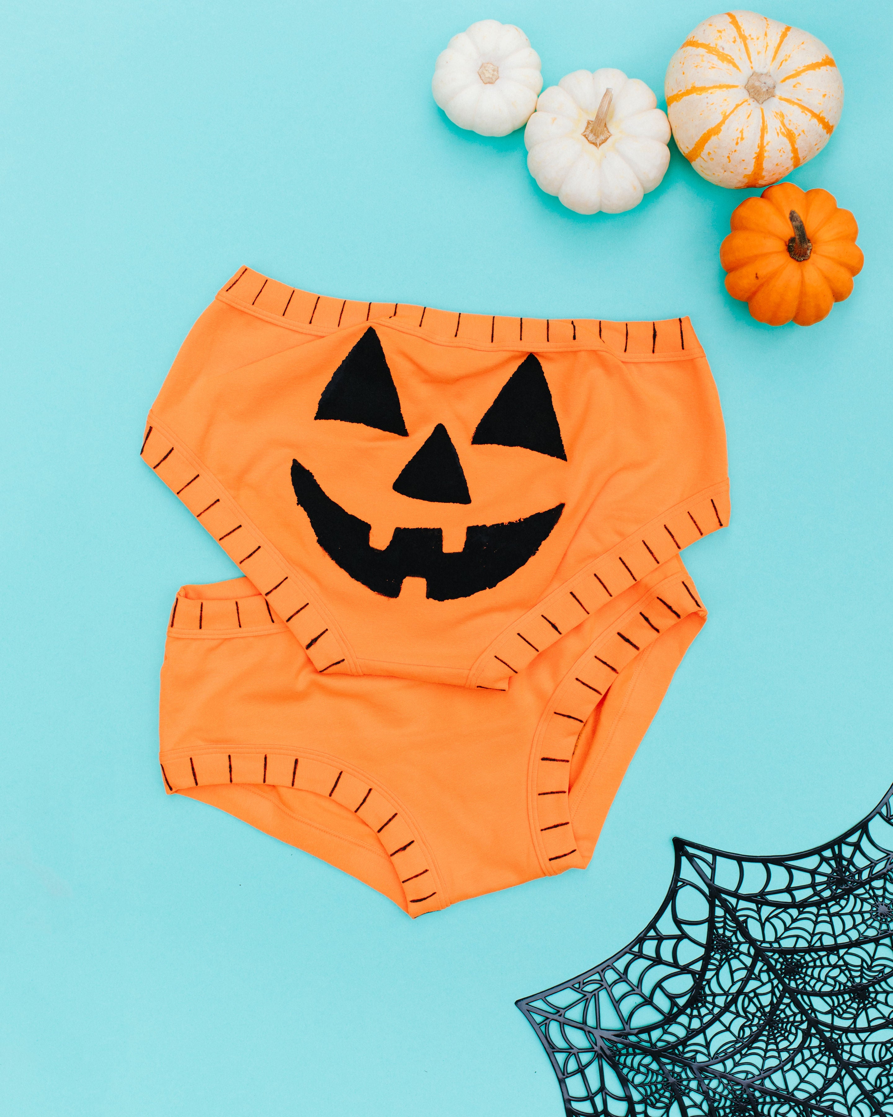 Flat lay of two pairs of Thunderpants Hipster style underwear with a hand printed Jack-O-Lantern face.