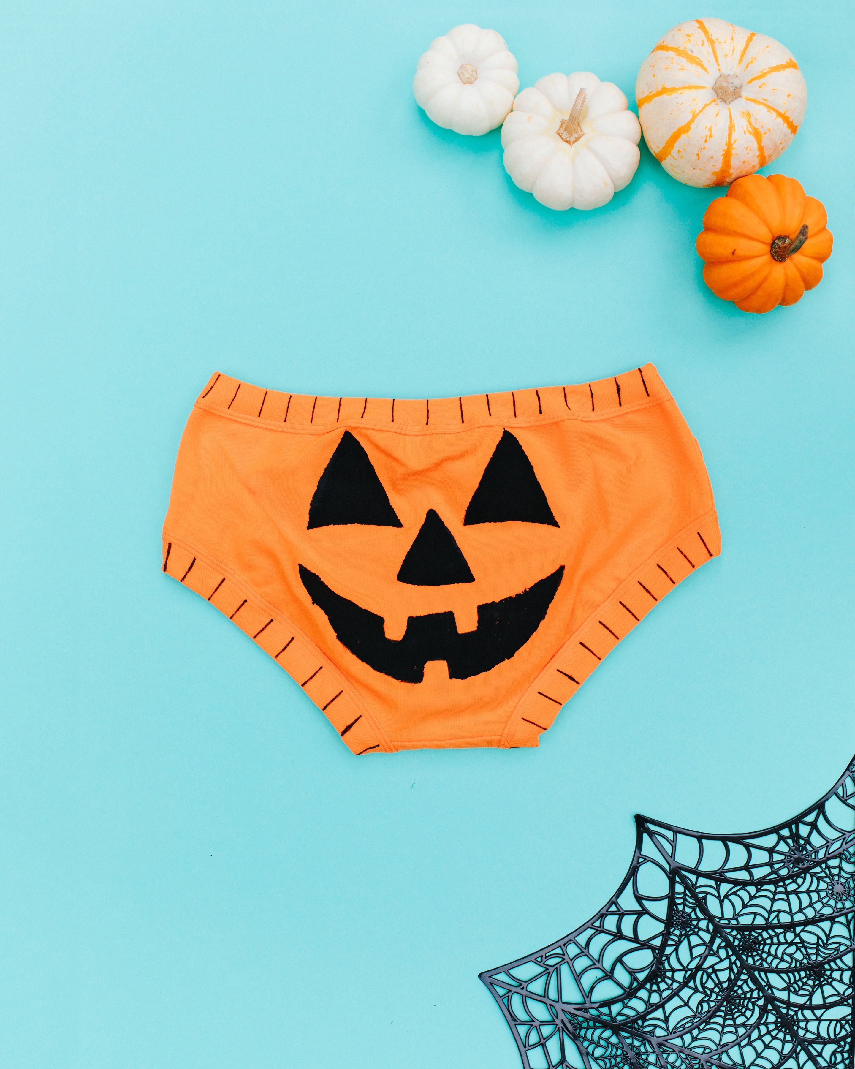 Flat lay of the back of Thunderpants Hipster style underwear in Oregon Sunstone with a hand printed Jack-O-Lantern face.