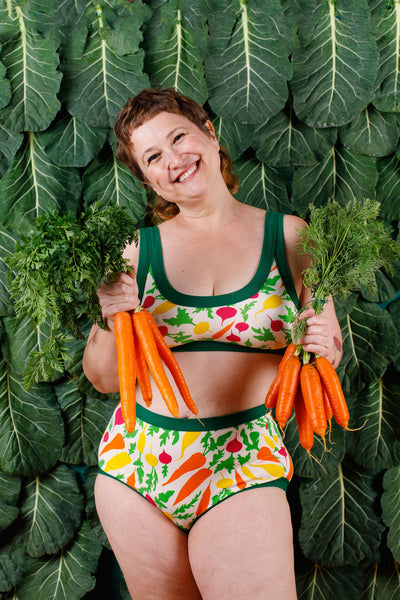 Model holding two bunches of carrots wearing Thunderpants Sky Rise style underwear and Bralette in Root Veggies.