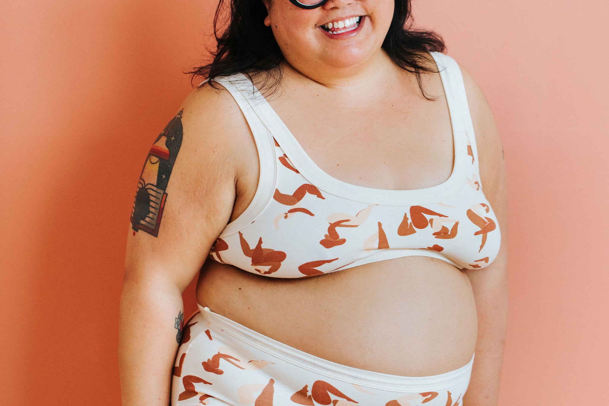 Model standing in front of a pink wall wearing Thunderpants Sky Rise style underwear and Bralette in Bodies in Motion.