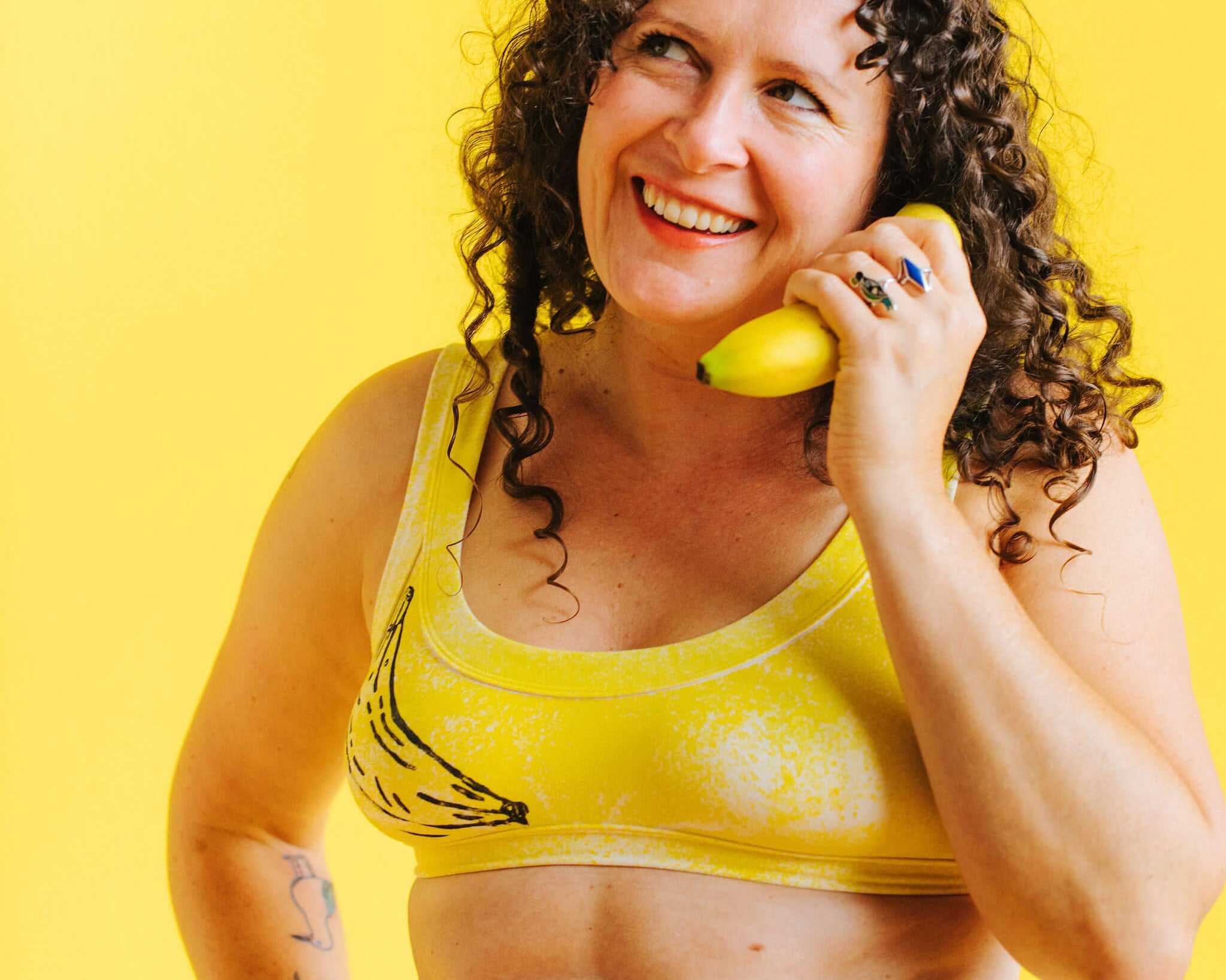 Model wearing Thunderpants Bralette in Banana Pitch - yellow with one black banana print.