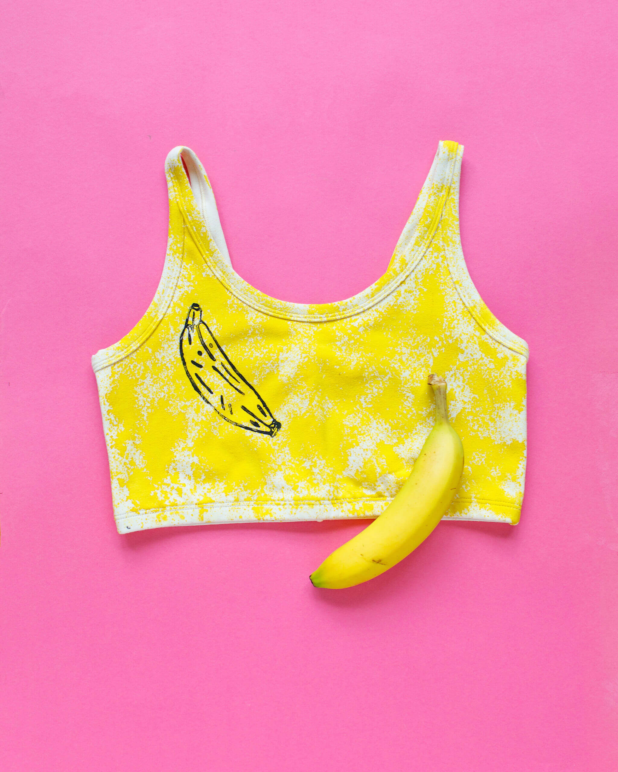 Flat lay of Thunderpants Longline Bra in Banana Pitch - yellow with one black banana print.