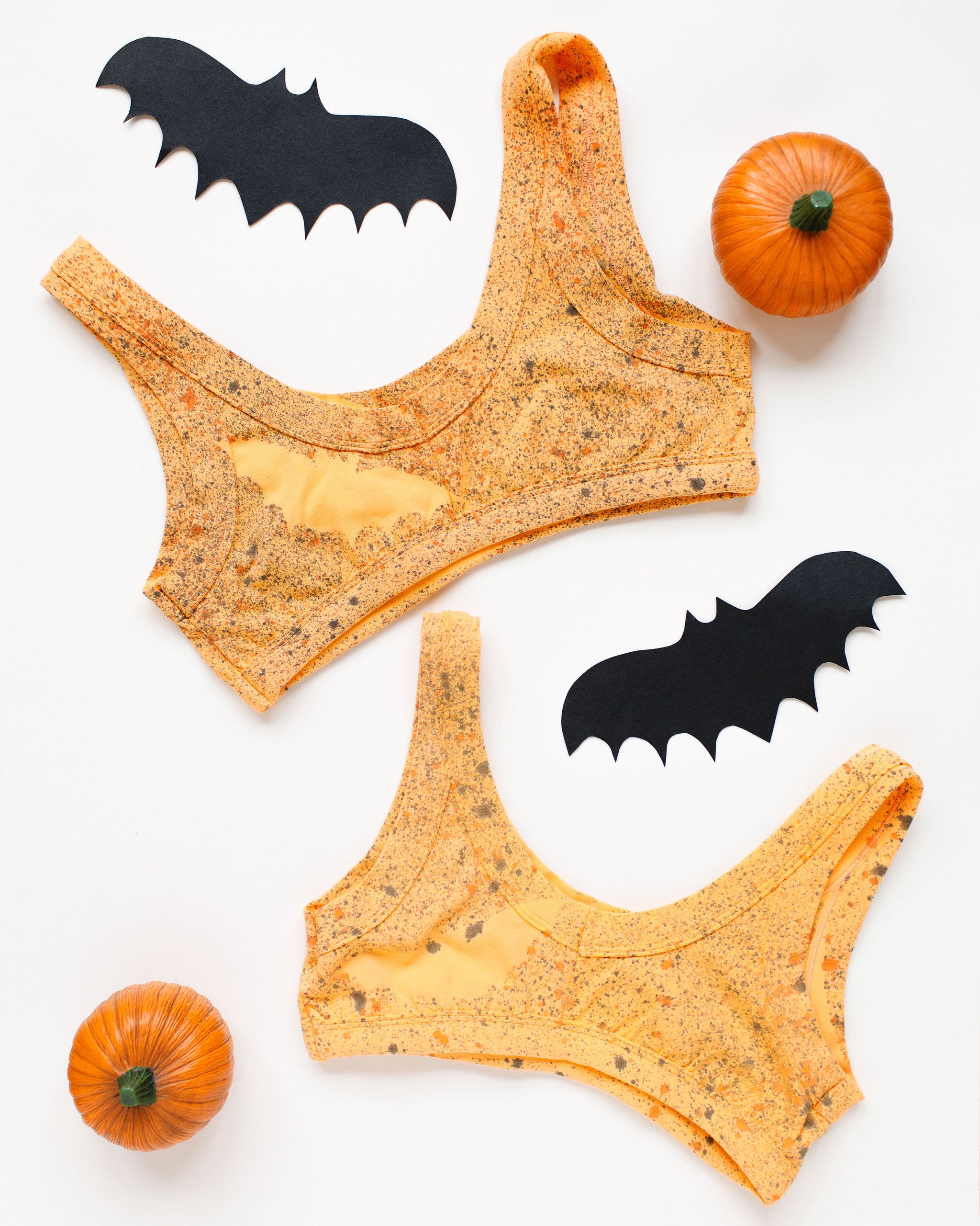 Flat lay of two Thunderpants Bralettes in Orange Sherbet with bats hand painted.