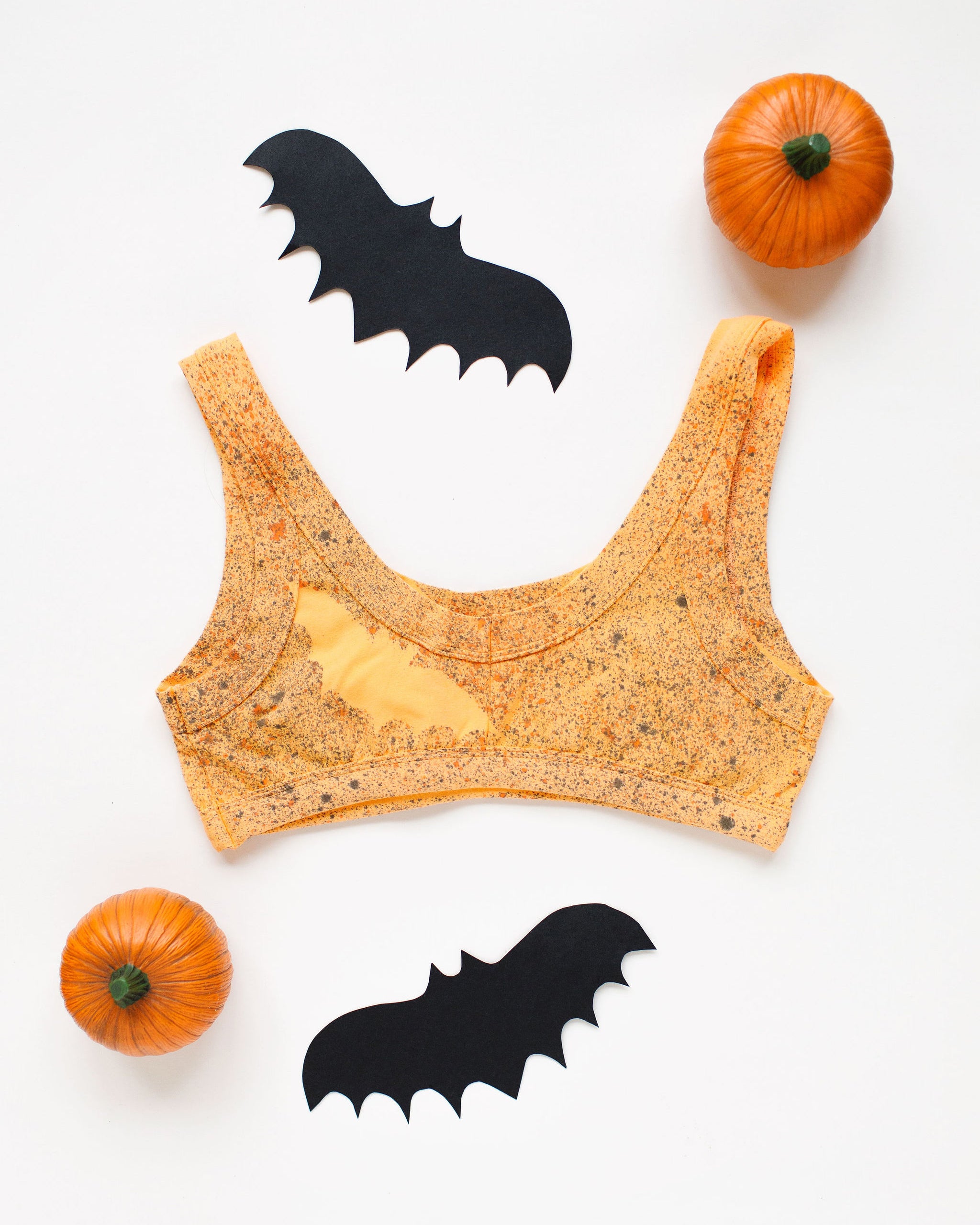 Flat lay of a Thunderpants Bralettes in Orange Sherbet with bats hand painted.