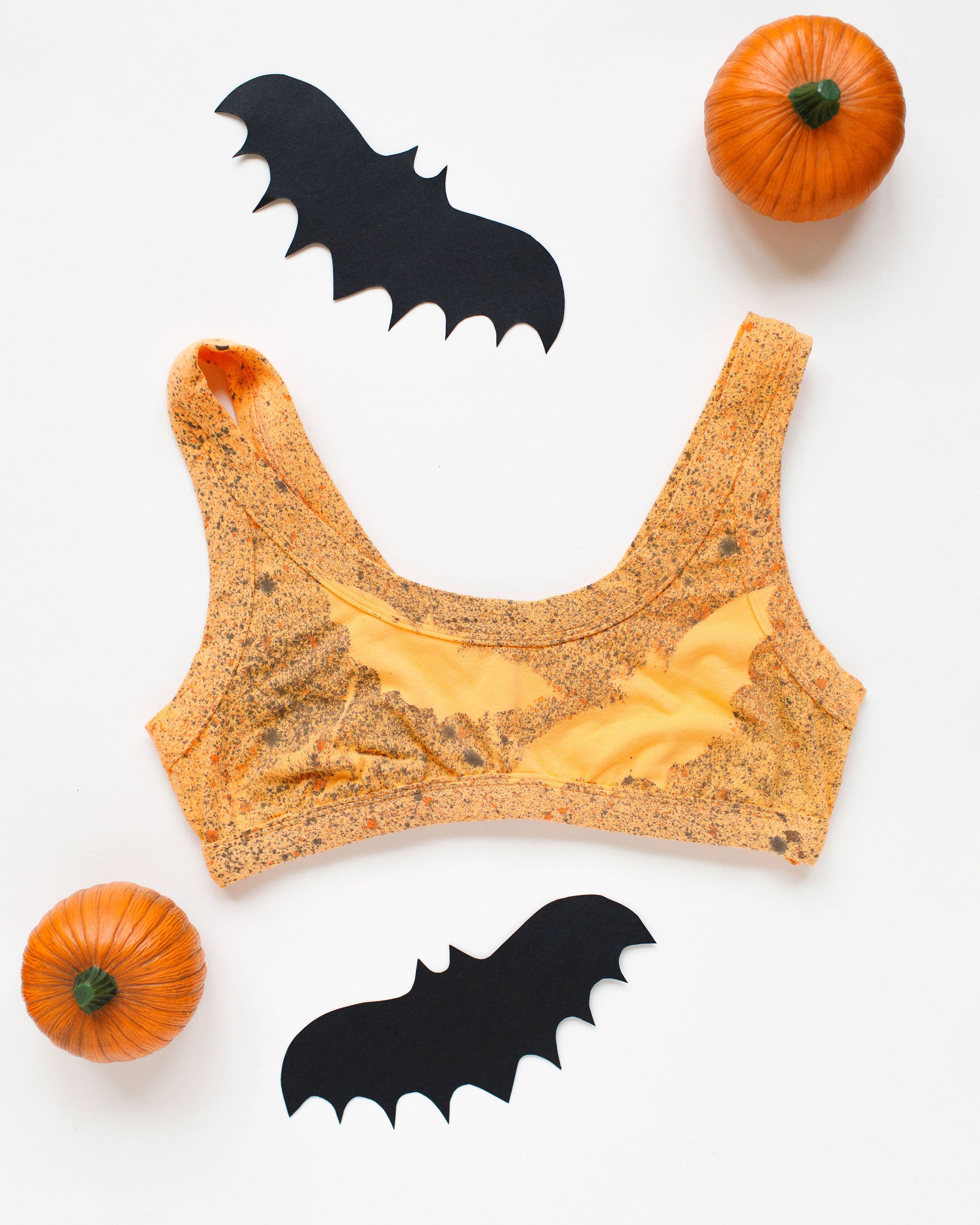 Flat lay of a Thunderpants Bralettes in Orange Sherbet with bats hand painted.