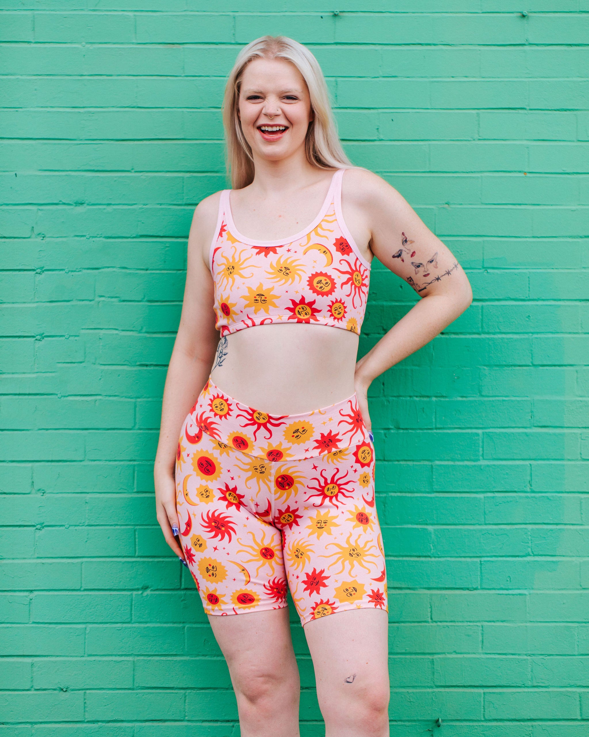 Model wearing Thunderpants Bike Shorts and Longline Bra in Luna y Sol print - pink, yellow, and orange suns and moons.