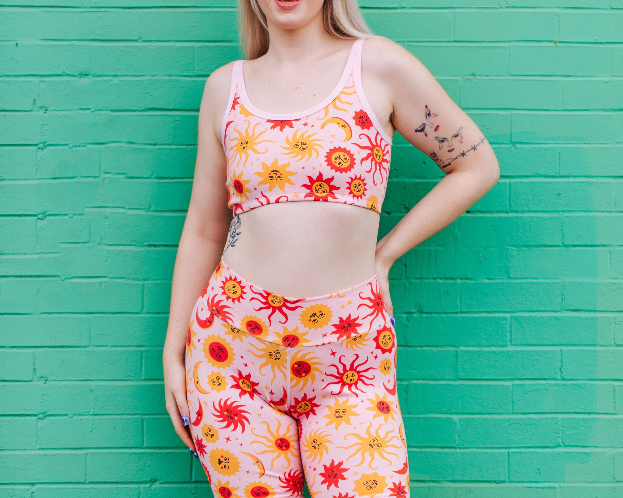 Model wearing Thunderpants Bike Shorts and Longline Bra in Luna y Sol print - pink, yellow, and orange suns and moons.
