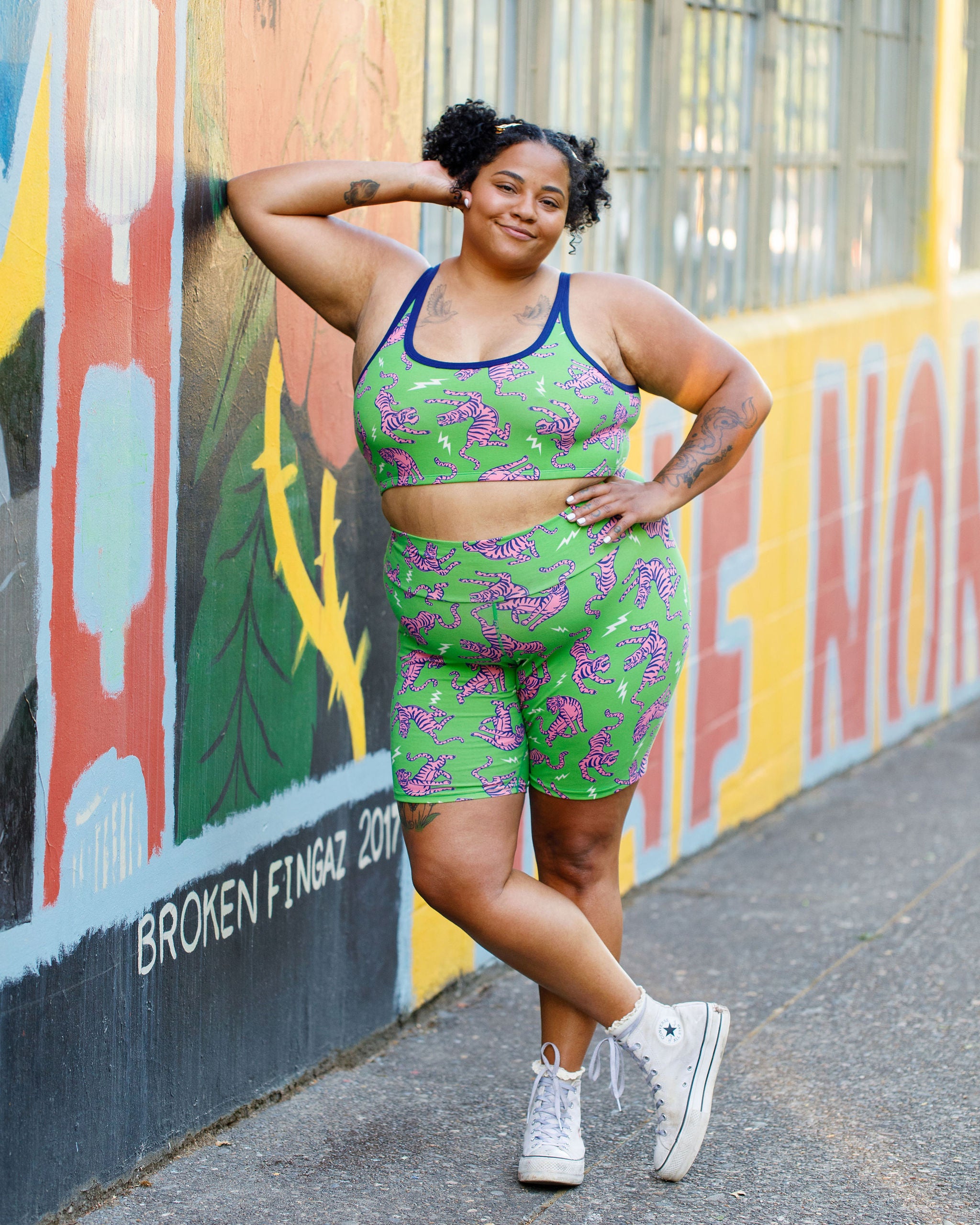 Model wearing Thunderpants organic cotton Bike Shorts and Longline Bra in Electric Tiger - green with pink and blue tigers and white lightning bolts.