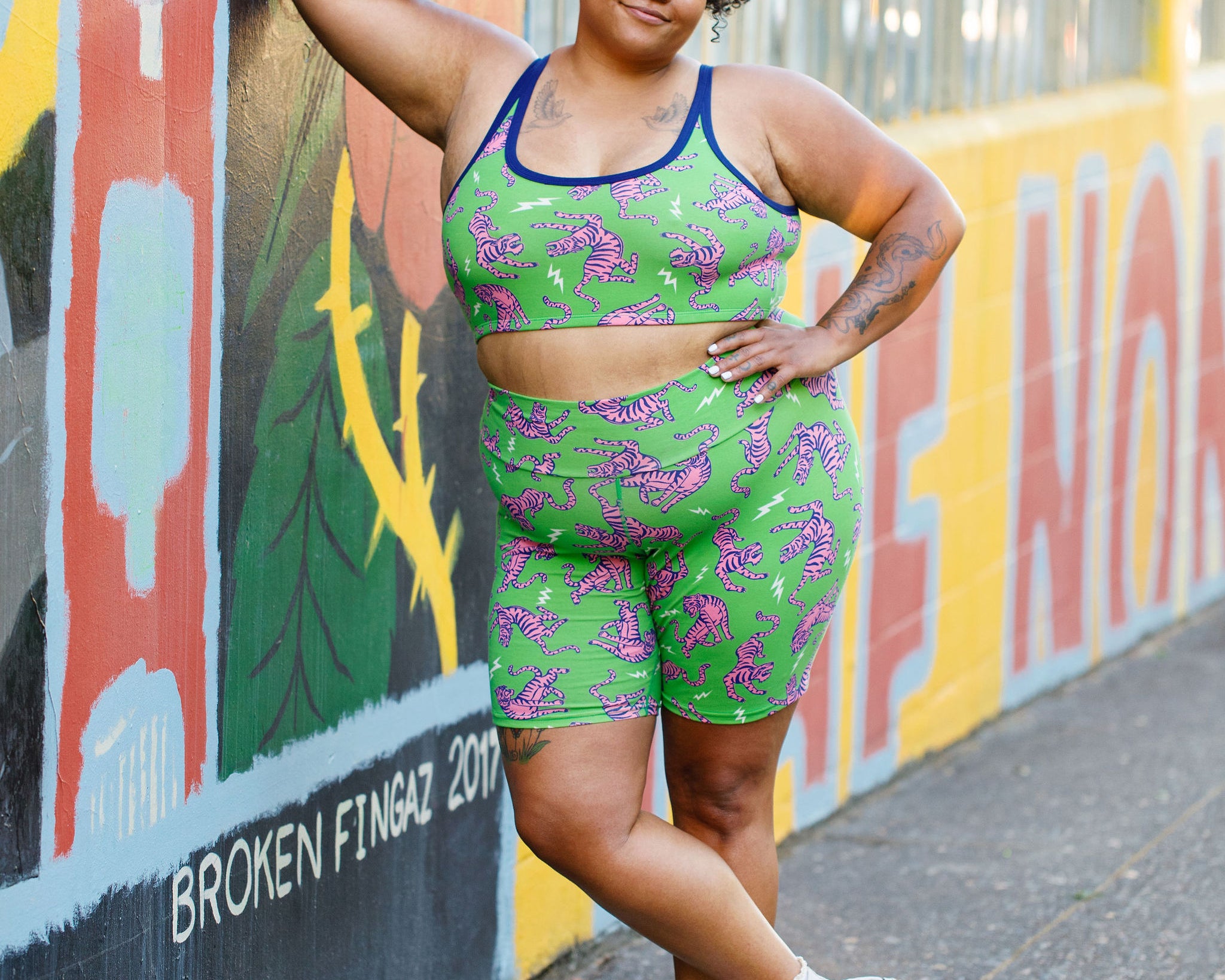 Model wearing Thunderpants organic cotton Bike Shorts and Longline Bra in Electric Tiger - green with pink and blue tigers and white lightning bolts.