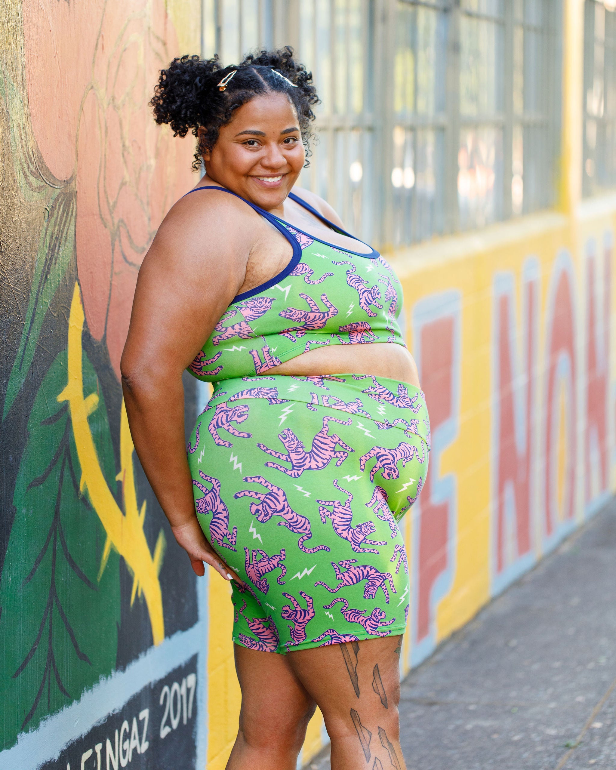 Model wearing Thunderpants organic cotton Bike Shorts and Longline Bra in Electric Tiger - green with pink and blue tigers and white lightning bolts.