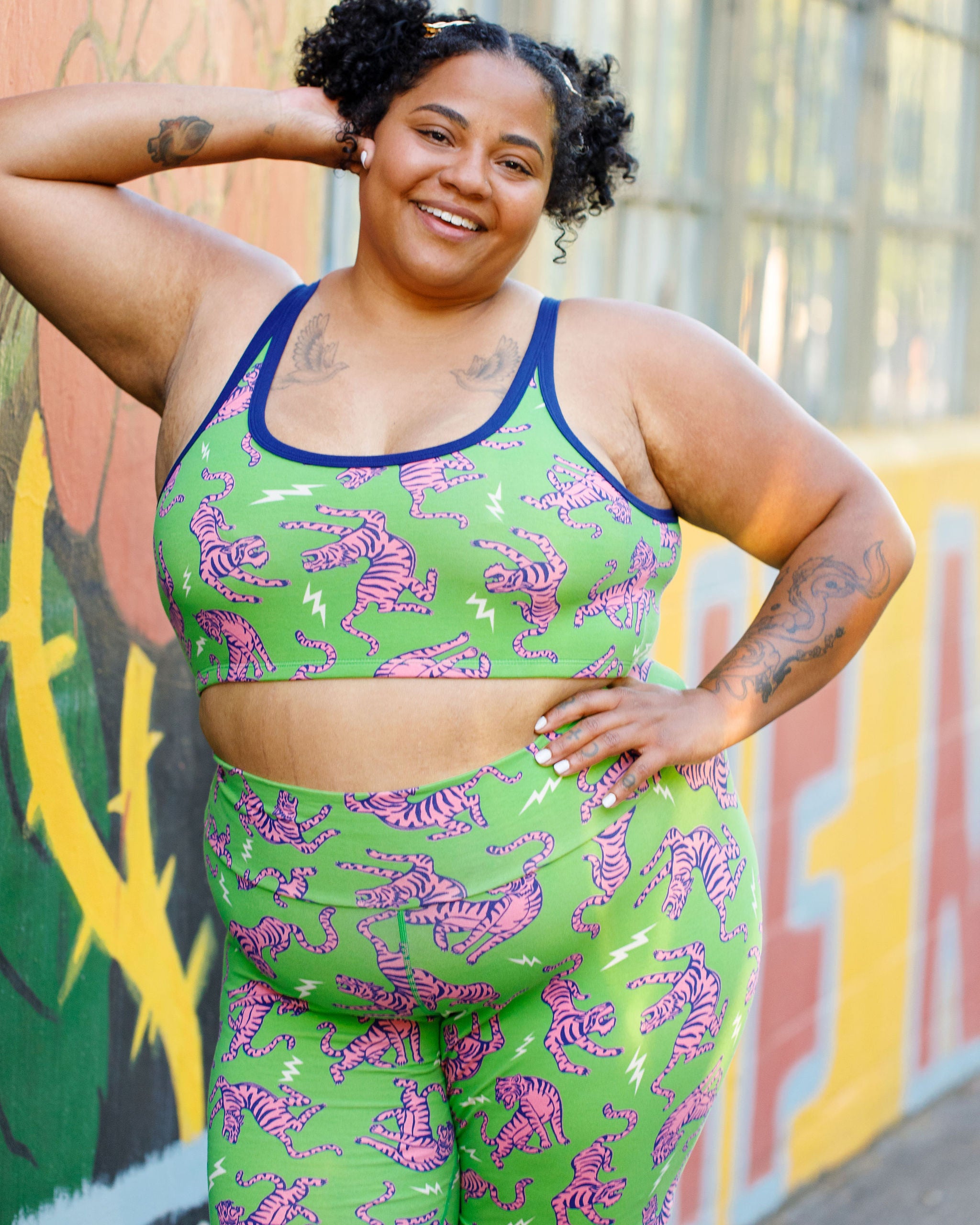 Model wearing Thunderpants organic cotton Bike Shorts and Longline Bra in Electric Tiger - green with pink and blue tigers and white lightning bolts.