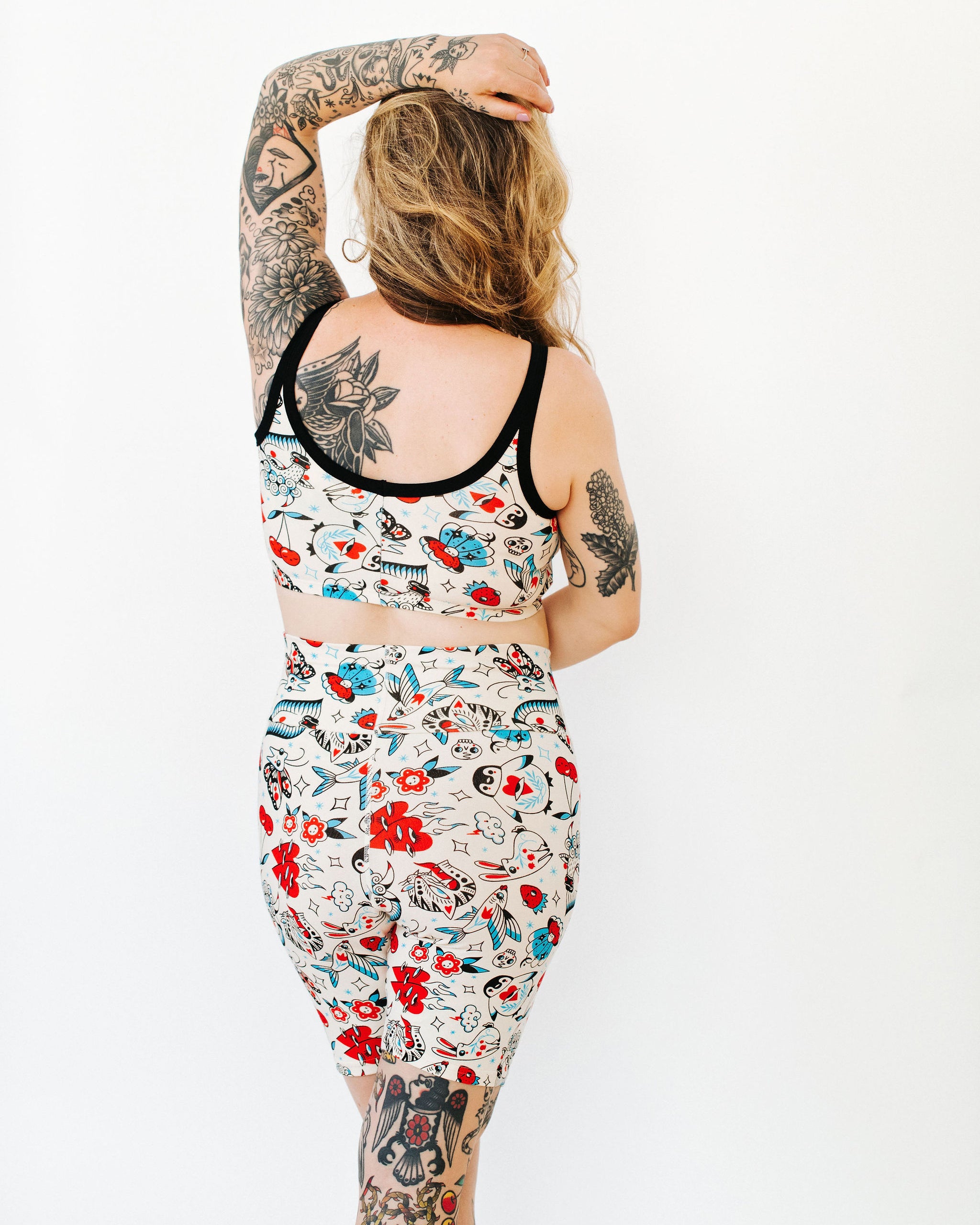Model wearing Thunderpants Bike Shorts and Longline Bra in Inked Up - a tattoo pattern with black, red, and blue. 